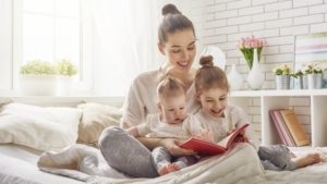 happy loving family. pretty young mother reading a book to her daughters