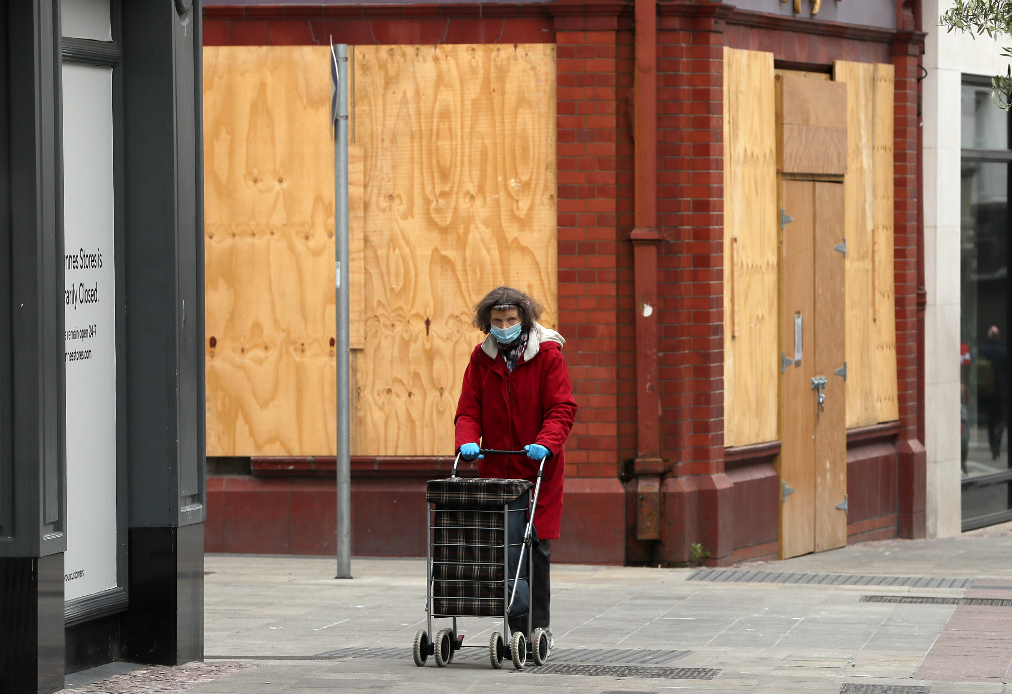 A woman walks past a boarded-up shop on Dublin's Grafton Street recession