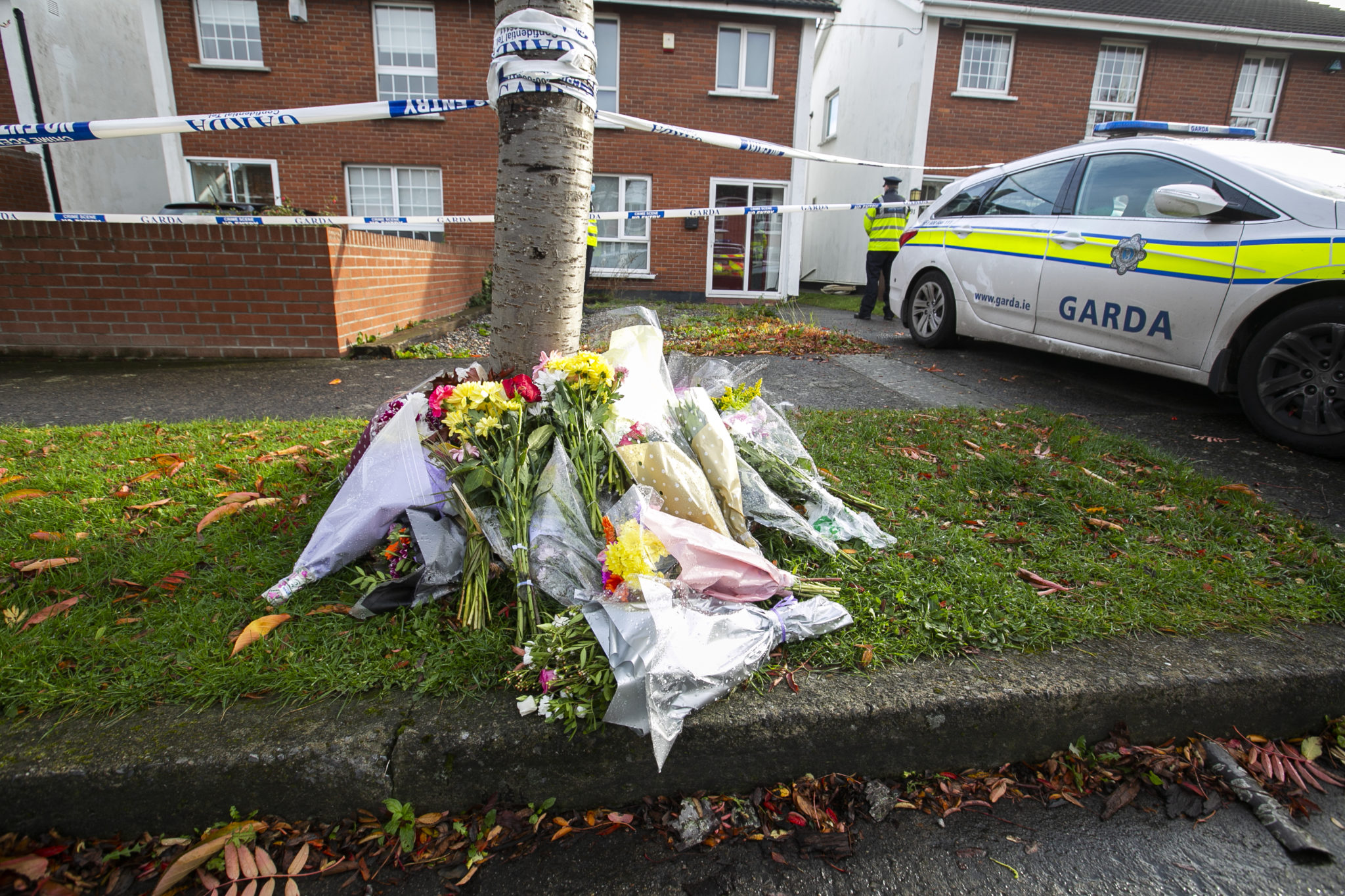 Gardaí and flowers outside the house in the Llewellyn Court estate in Ballinteer in which the bodies of 37-year-old Seema Banu, her daughter Asfira, and her son Faizan were found murder