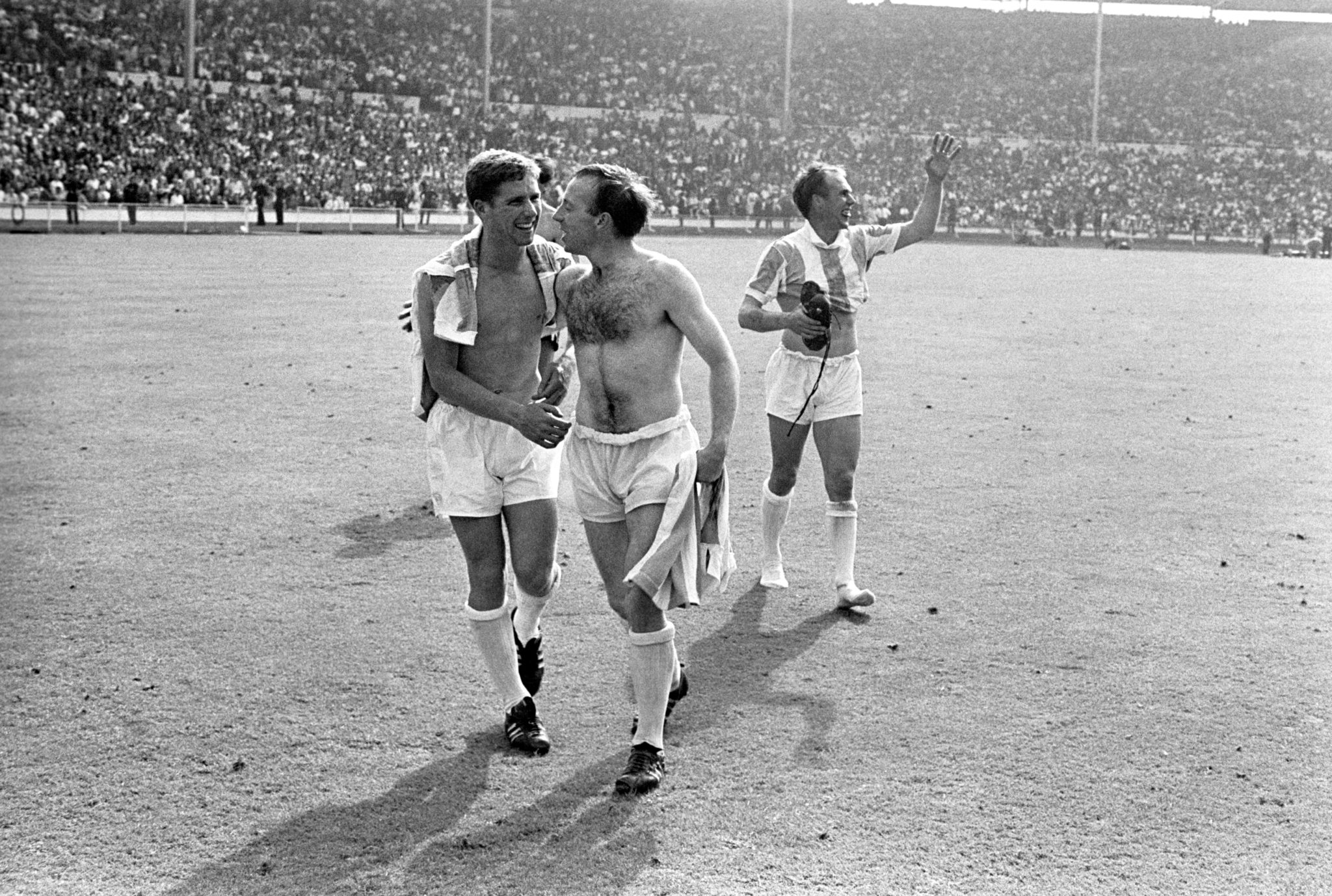 (L-R) England's Alan Ball and Nobby Stiles celebrate victory as teammate Ray Wilson waves to the crowd
