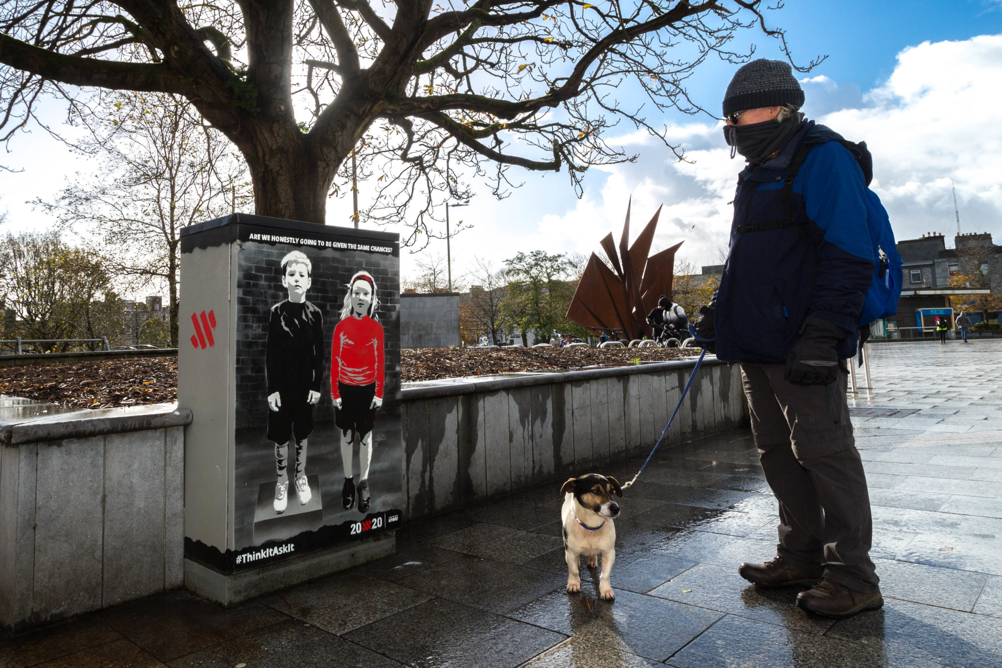 A man and dog pass the mural in Eyre Square.