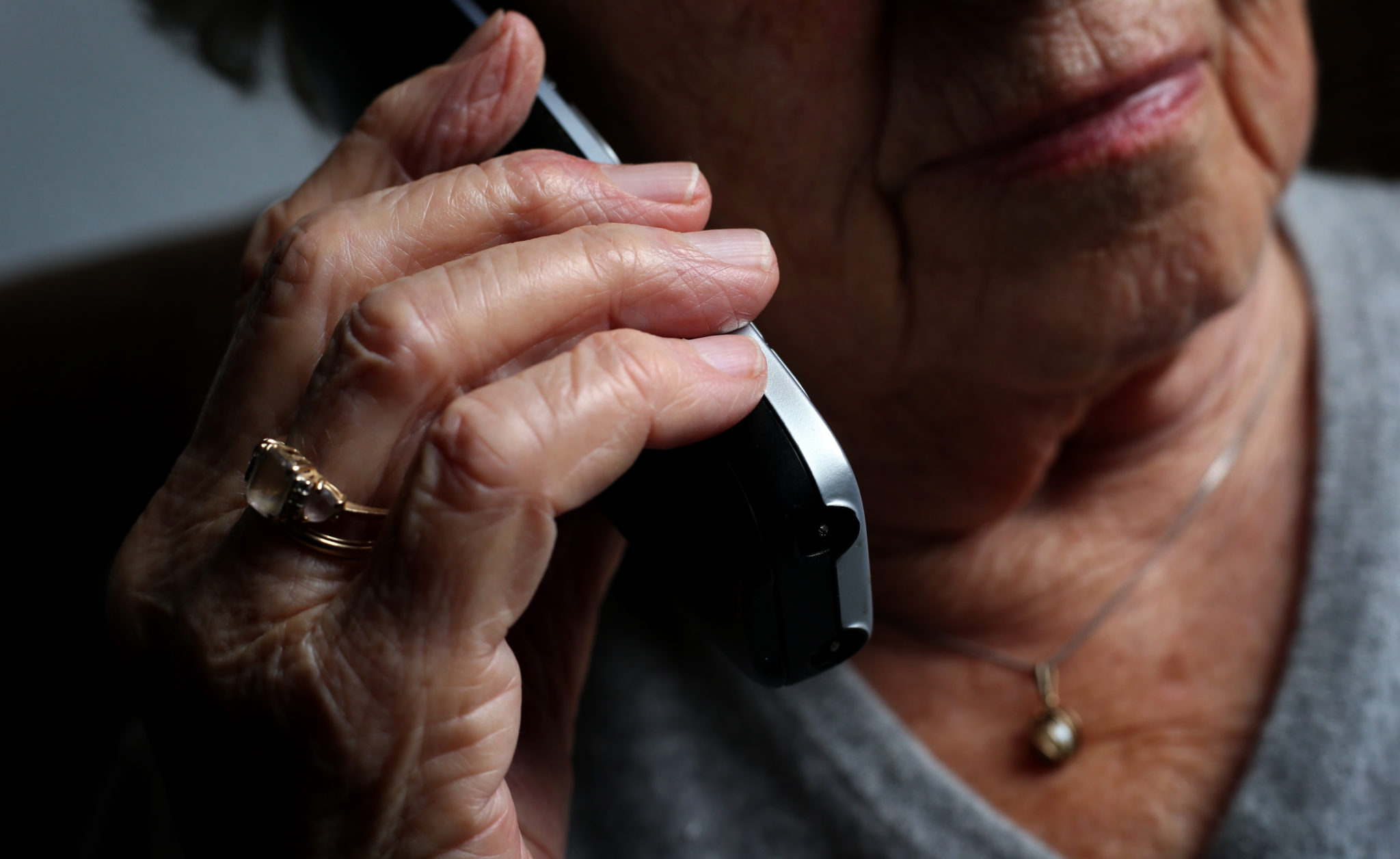 An elderly woman using a cordless landline phone.