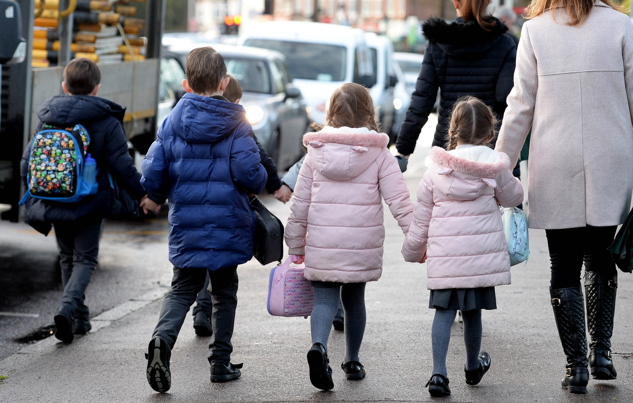 Parents walk their children to school in Hornchurch, Essex, past stationary vehicles near to the school grounds. PA Photo. Picture date: Friday January 17, 2020. Photo credit should read: Nick Ansell/PA Wire