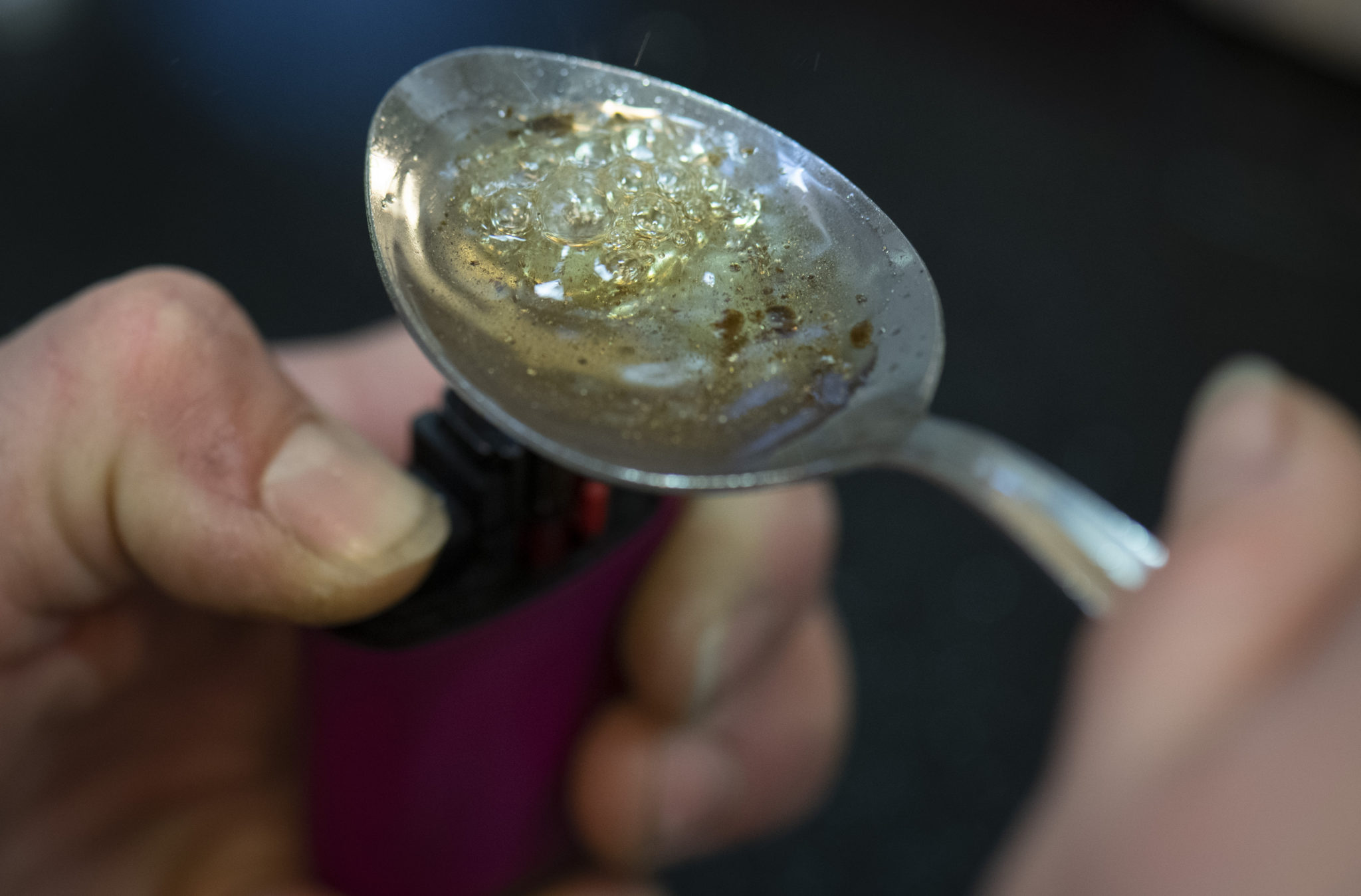 A woman boils a portion of crack cocaine in a spoon