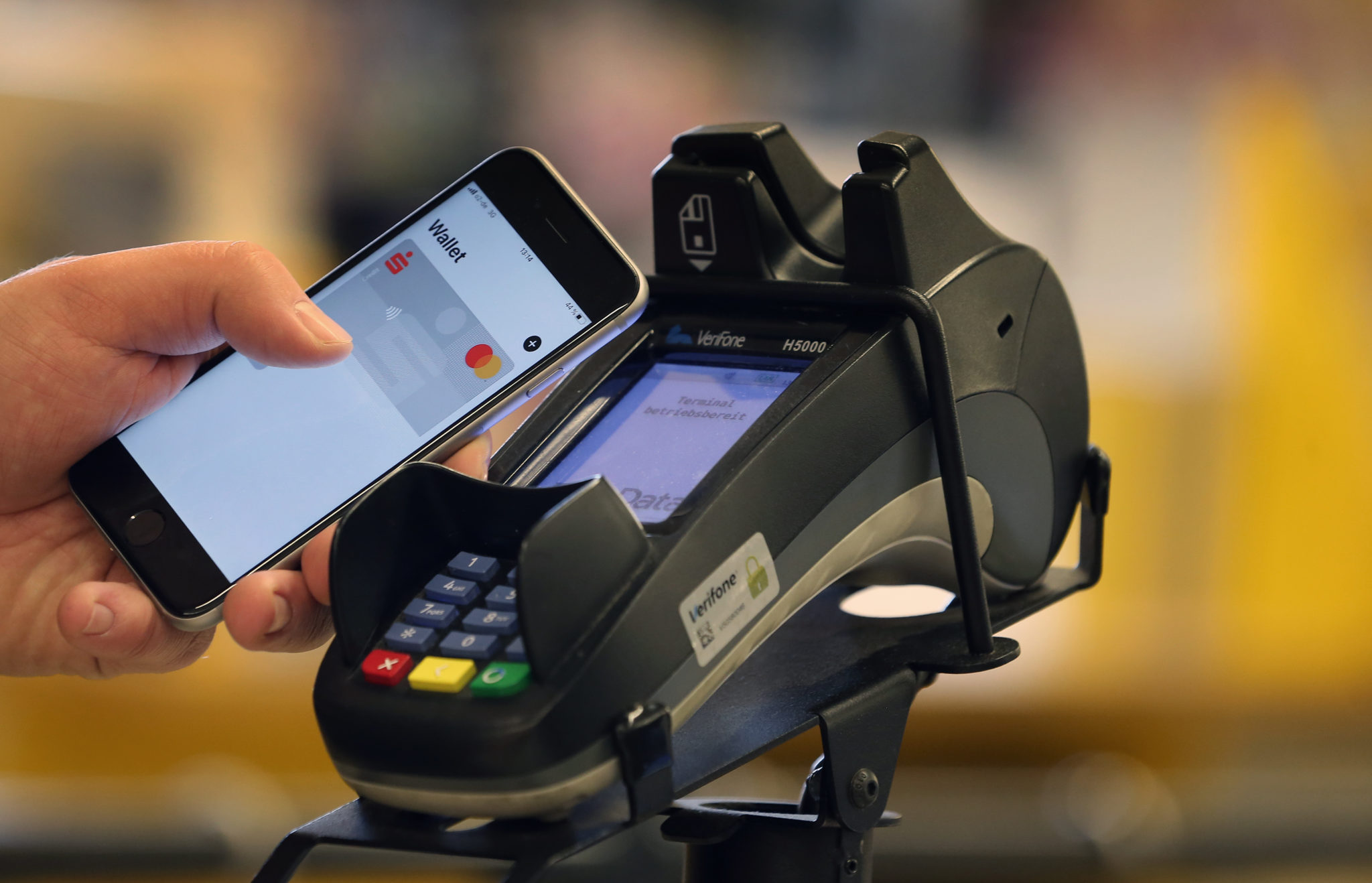 A smartphone is held at a payment terminal at the checkout of a supermarket in January 2020