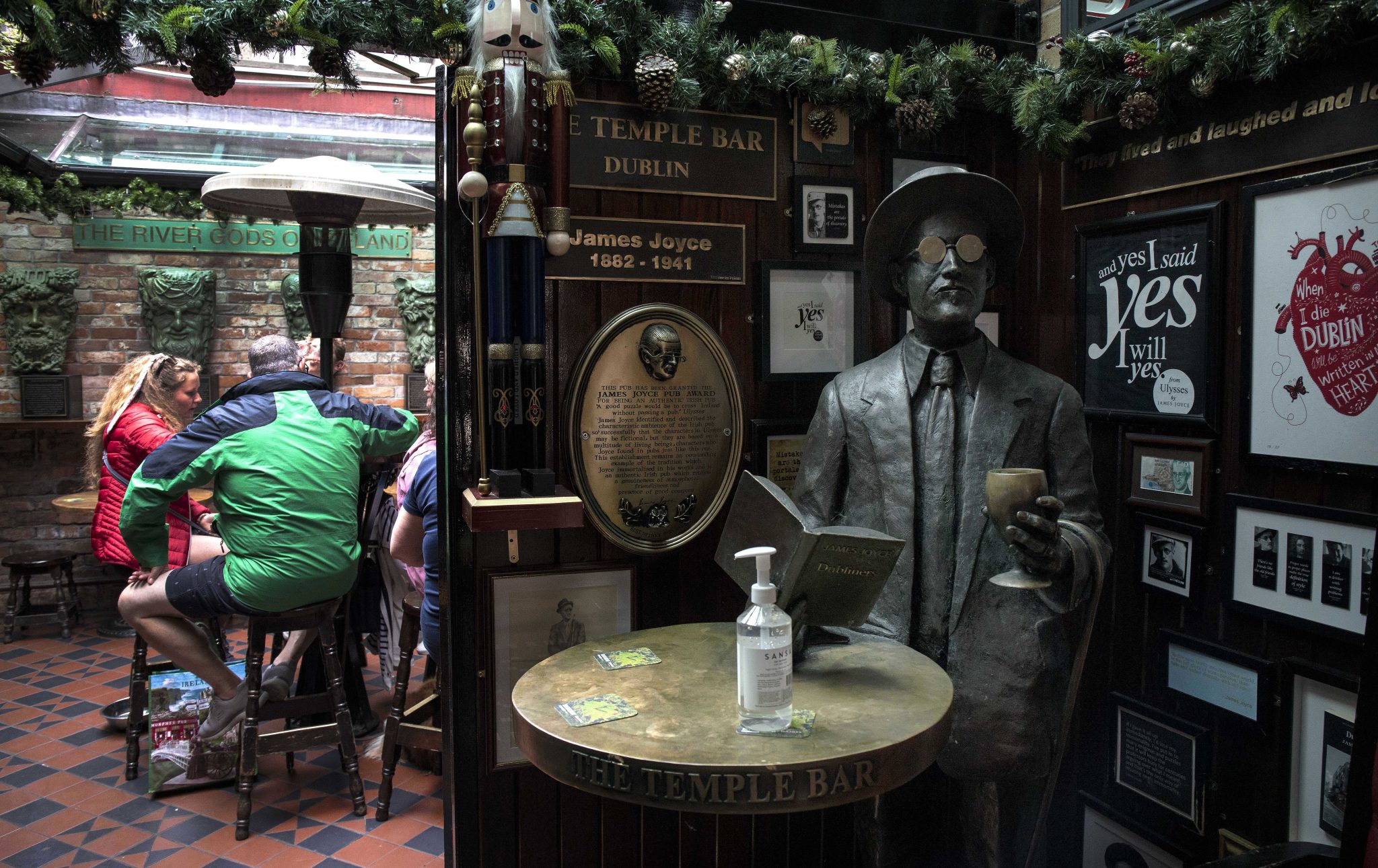 A bottle of hand sanitiser sits on a table beside a statue of Author, James Joyce in The Temple Bar in Dublin, 26-07-2021
