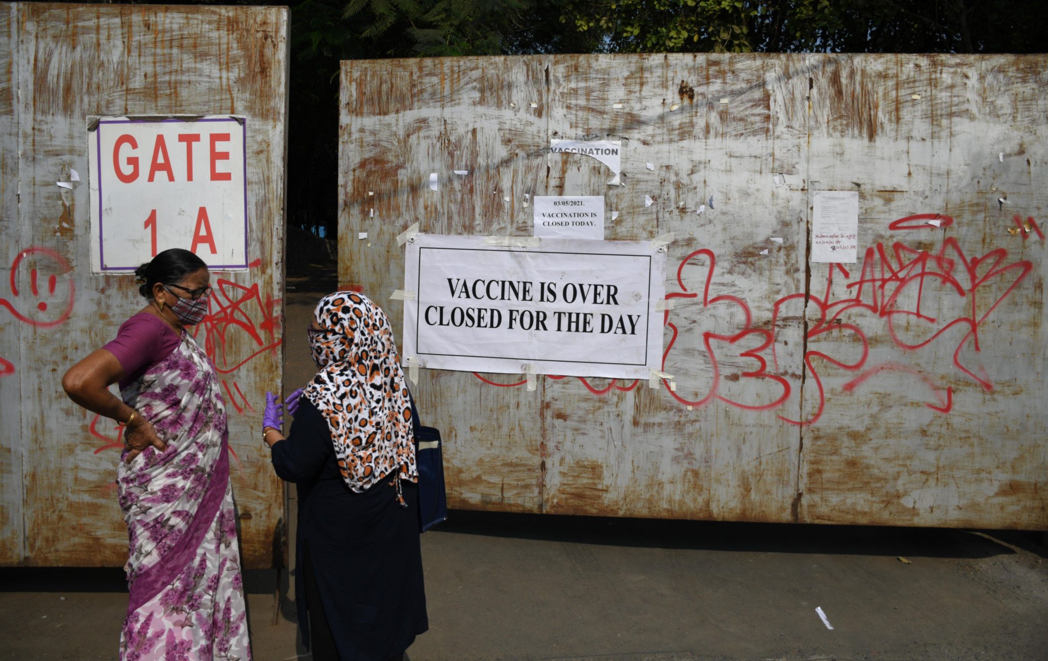 Women stand near the gate of a vaccination centre with a notice saying ''vaccine over closed for the day'' in Mumbai, India. Image: Ashish Vaishnav/SOPA Images/ZUMA Wire/Alamy