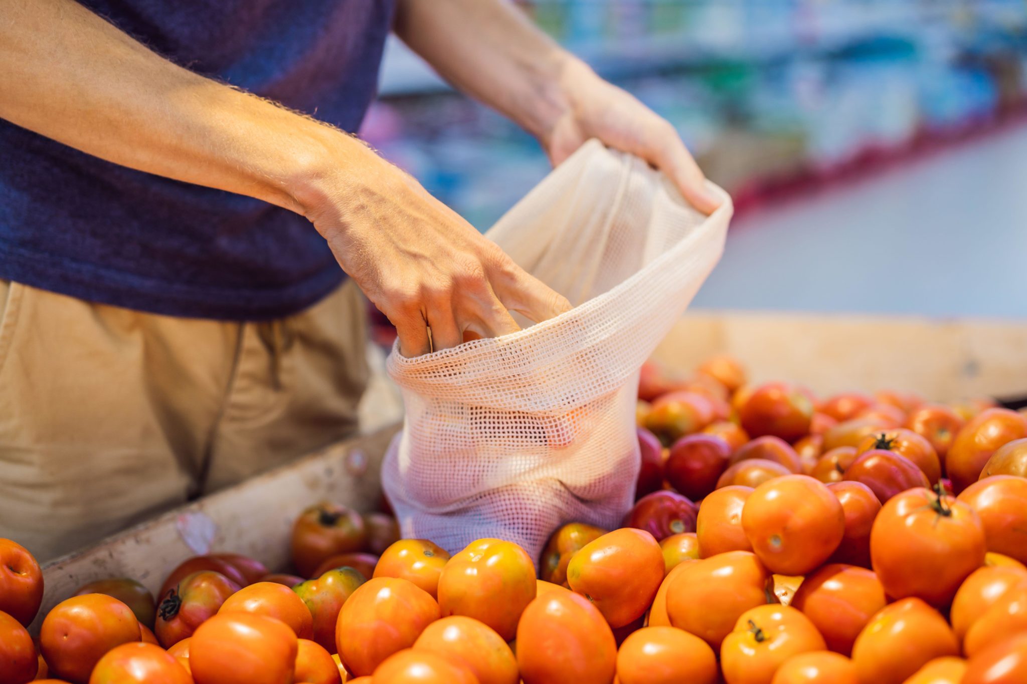 A man chooses tomatoes in a supermarket with a reusable bag in April 2020 in Thailand.