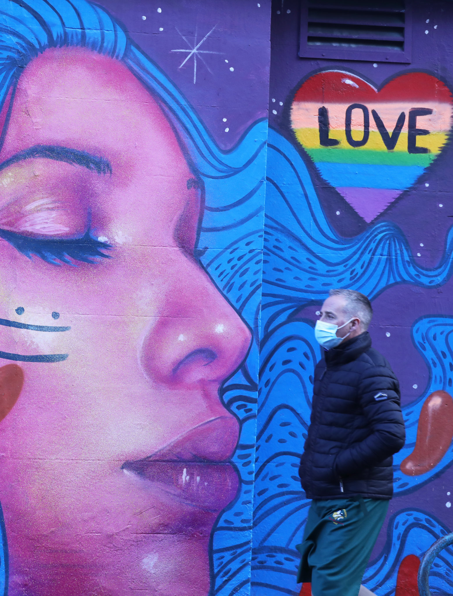 A man wearing a mask walks past a mural on Lower Baggot Street in Dublin, 08-01-2022. Image: Leah Farrell/RollingNews