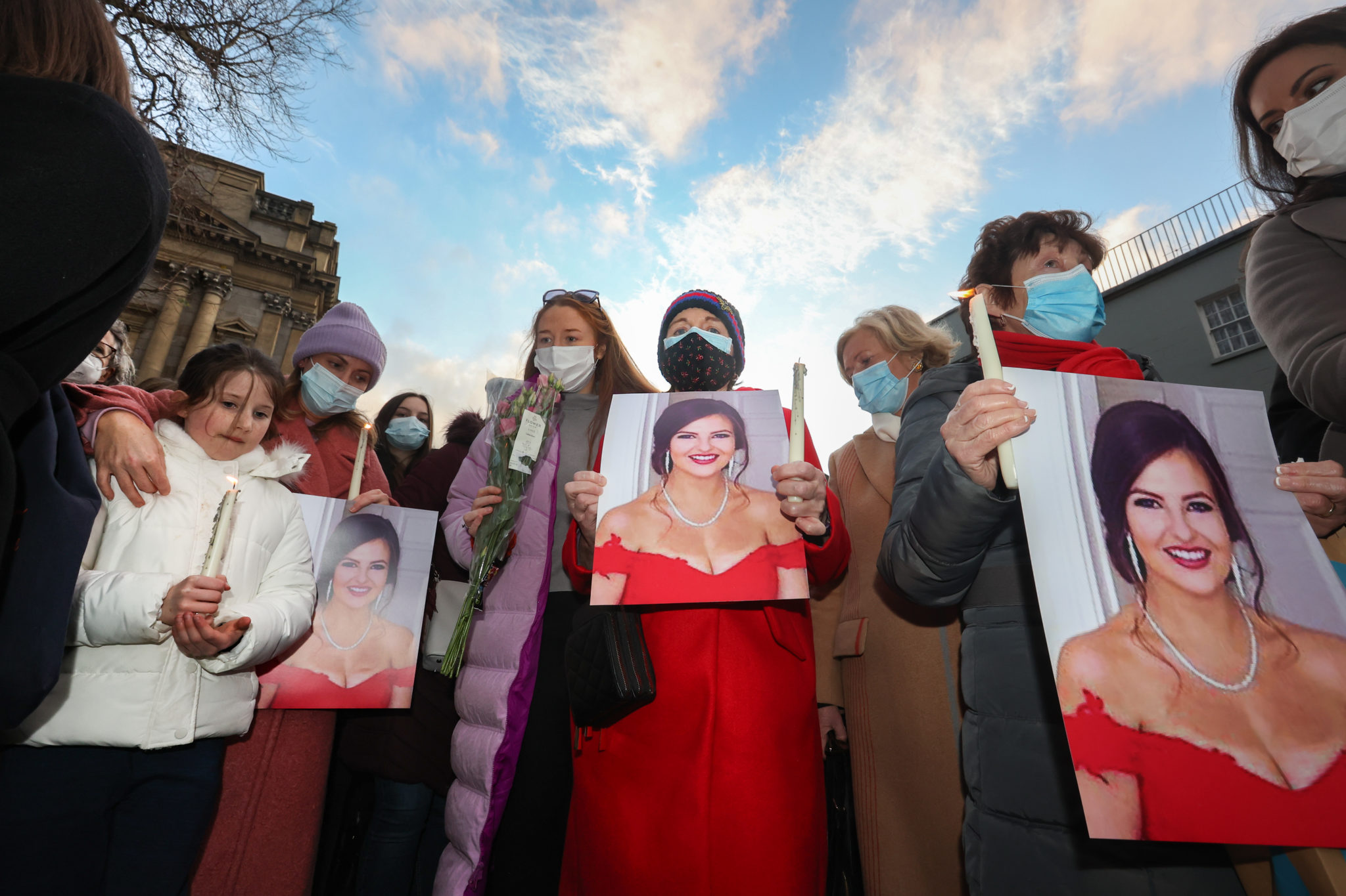 Women hold photos of Ashling Murphy outside Dáil Éireann in Dublin as part of a vigil.