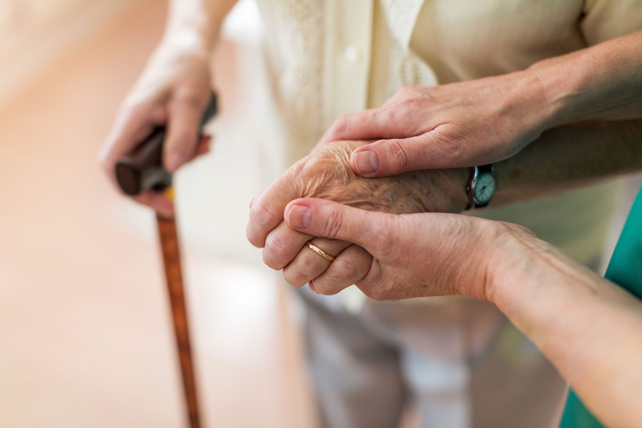 2BAJKRR Nurse consoling her elderly patient by holding her hands
