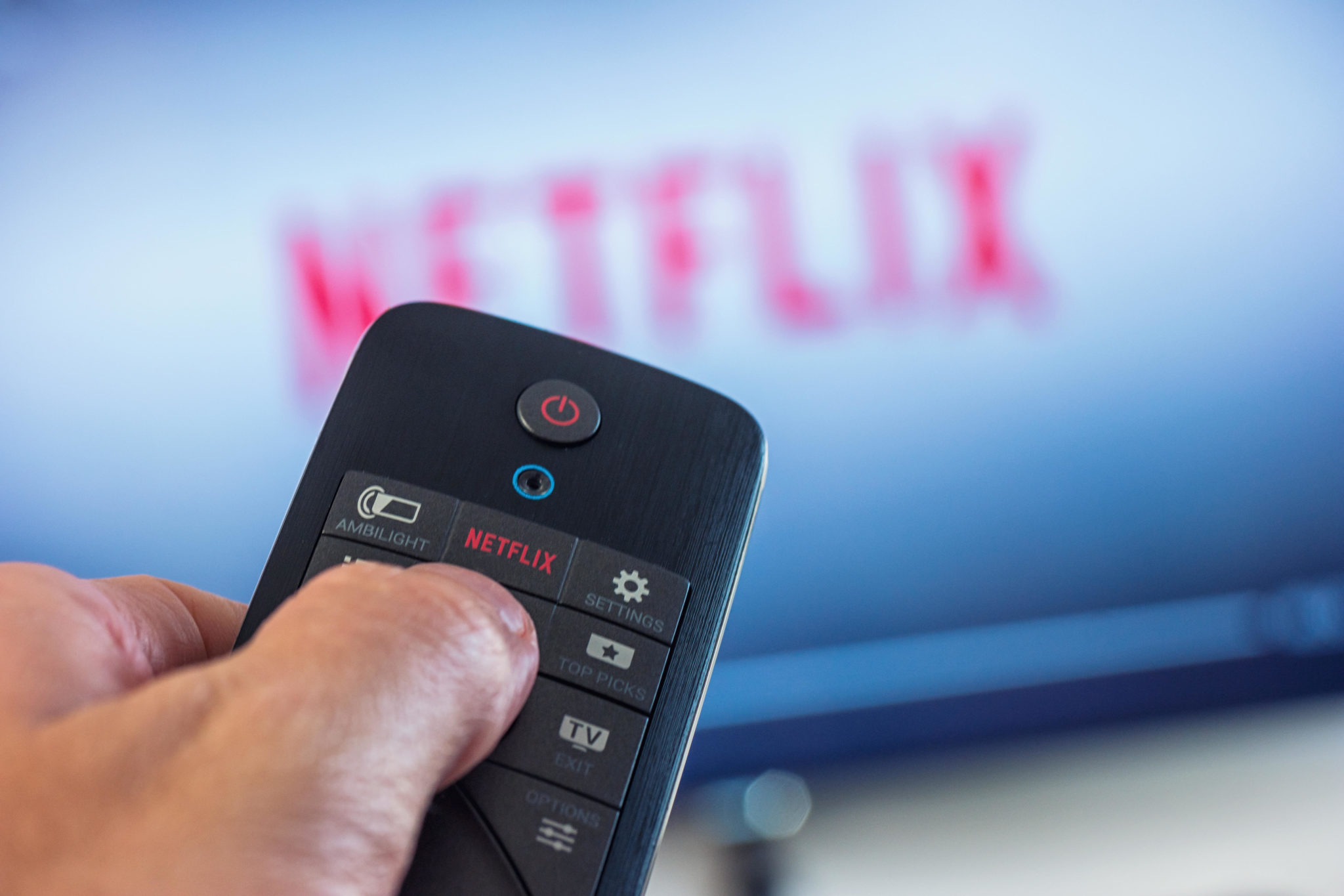 A man holds a remote control and selects a film from Netflix in October 2017.