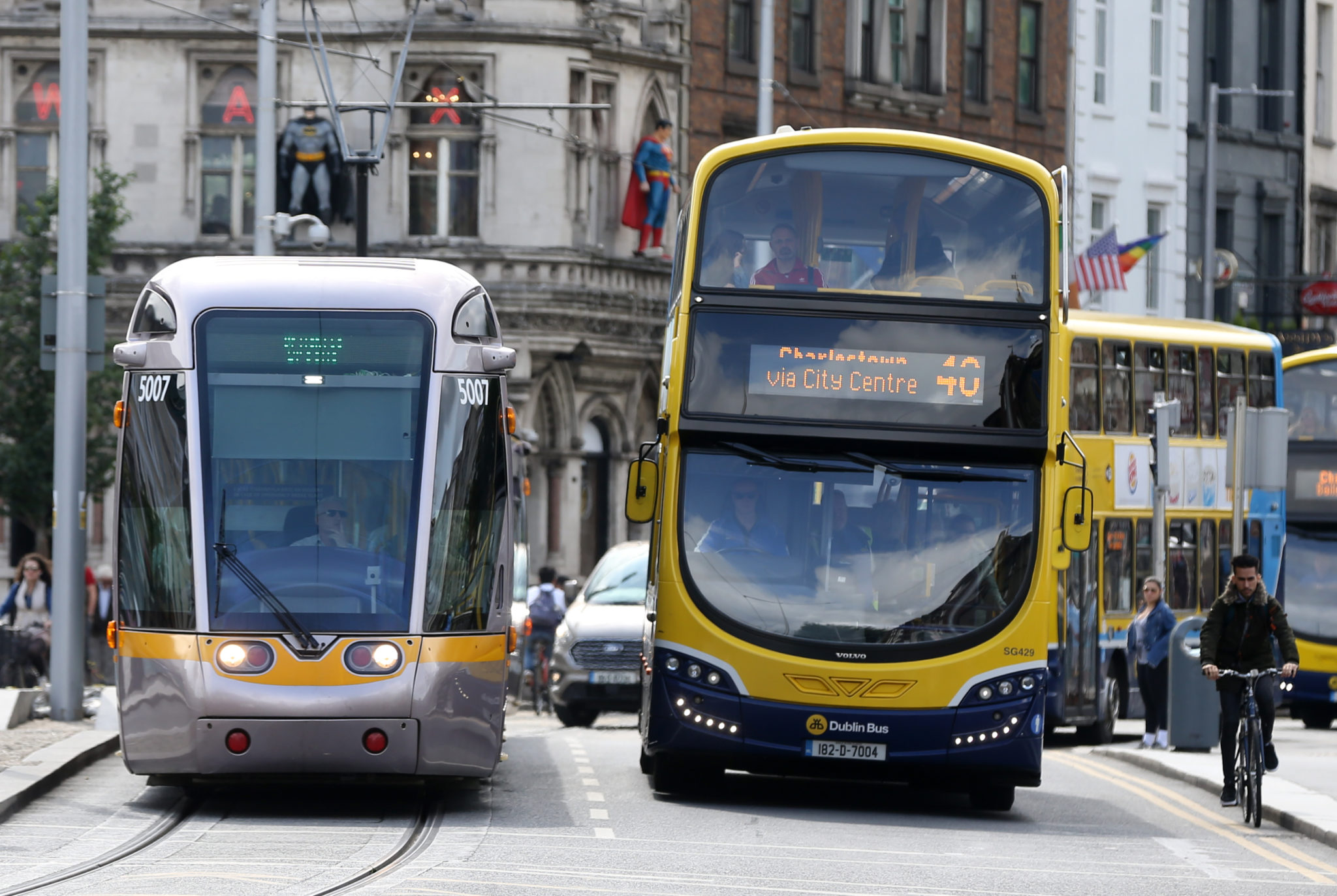 Luas trams beside a Dublin Bus, while a Cyclist passes by, in Dublin city Center