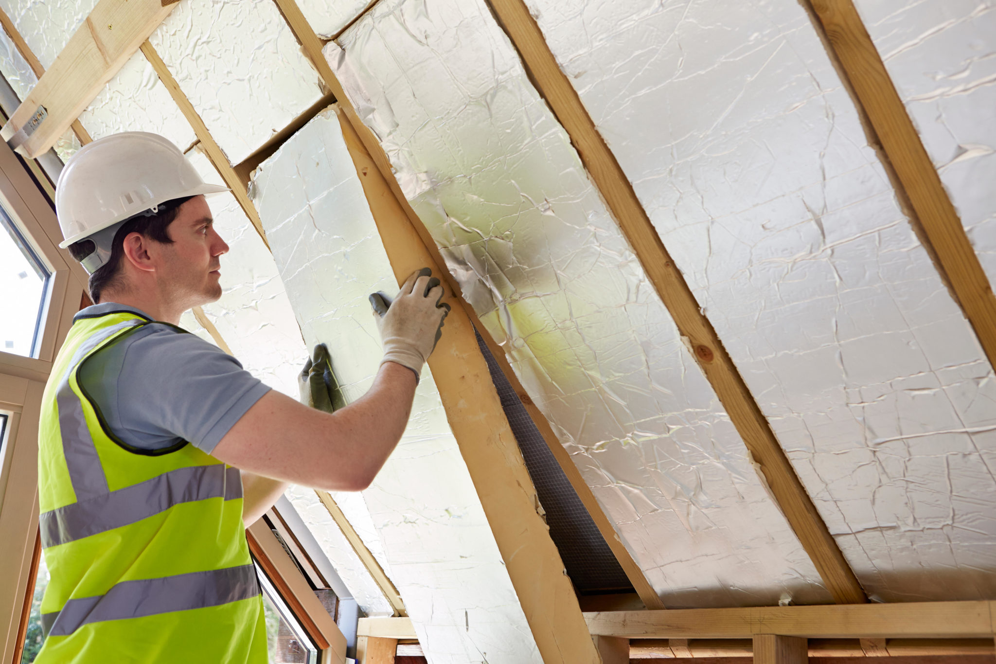 Builder Fitting Insulation Into Roof Of New Home. Image: Ian Allenden / Alamy Stock Photo