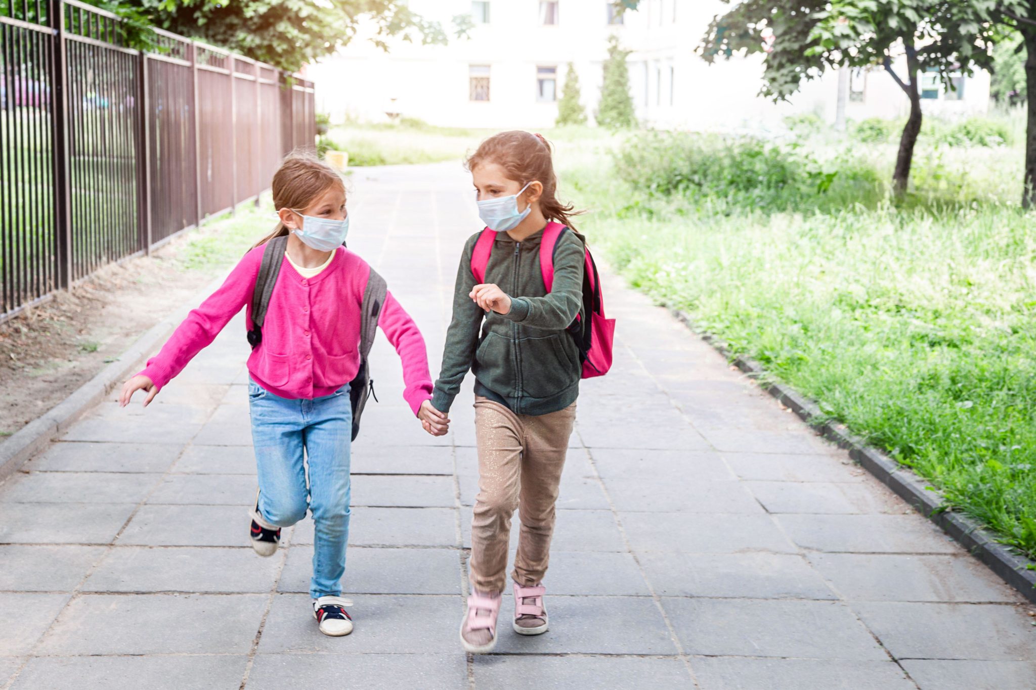 File photo shows two girls running to school wearing protective face masks