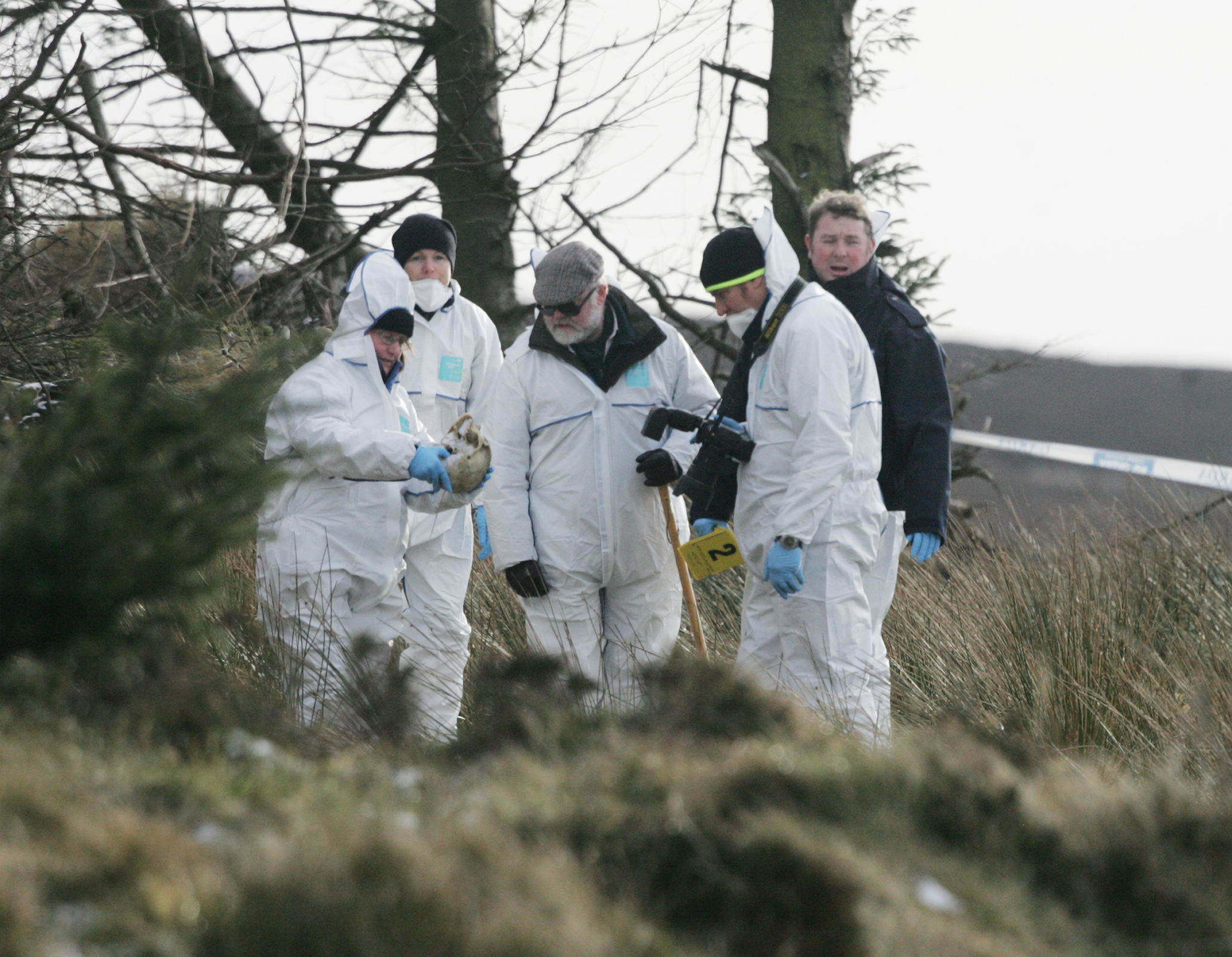 Deputy State Pathologist Dr Michael Curtis (centre with sunglasses) at the scene where remains of a man were found by a walker off the Military Road near Viewpoint, 01-02-2010