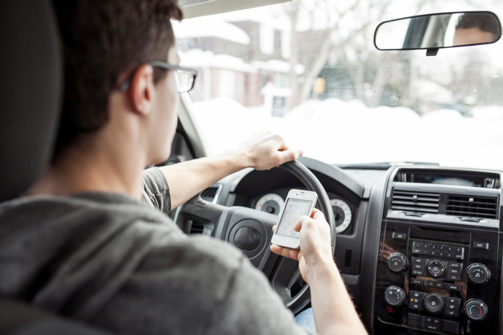Caucasian man using cell phone and driving car.