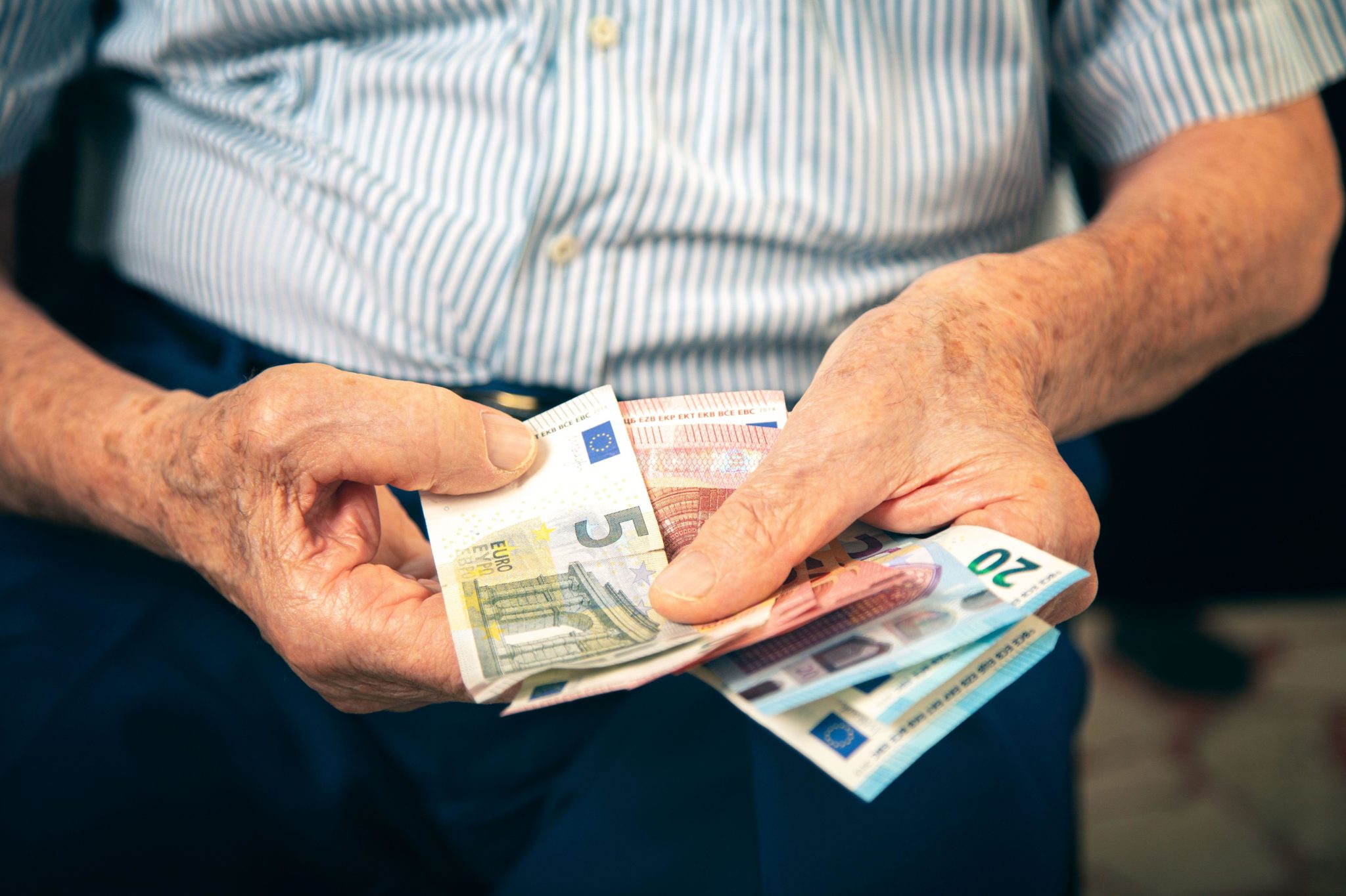 An older man counting Euro notes.