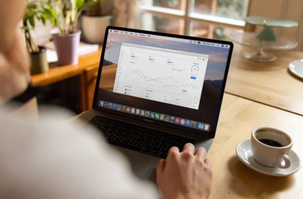 remote working. Image shows a person in front of a laptop with a cup of coffee at the side of the laptop.