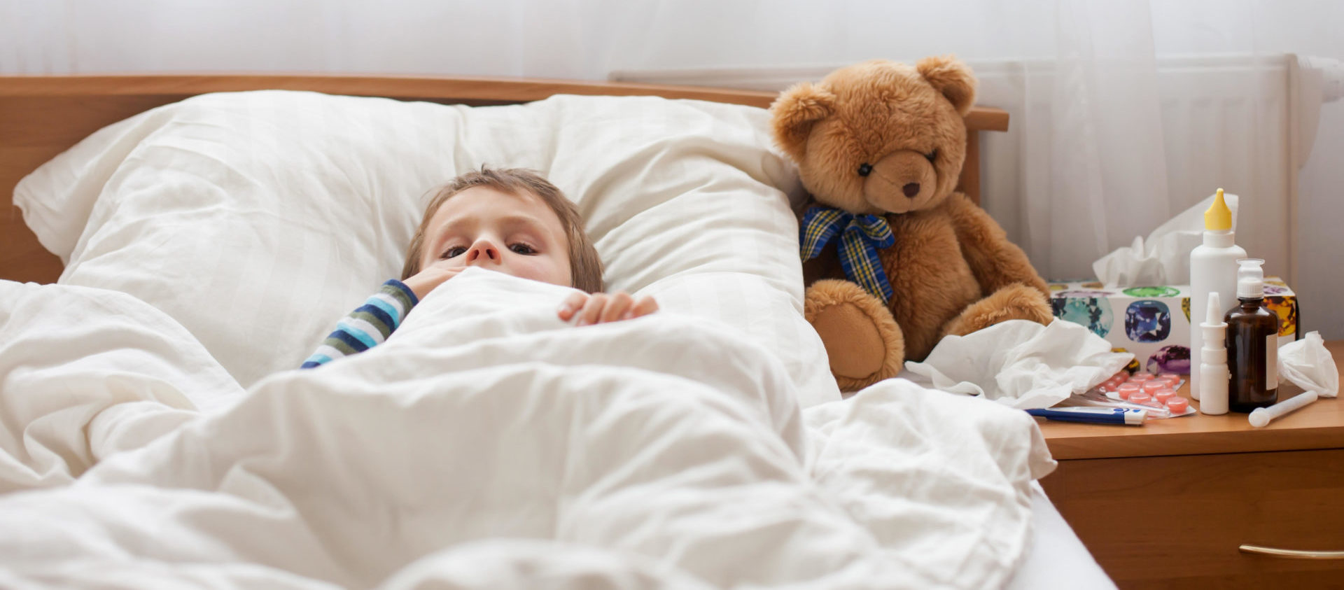 Sick child lying in bed with a fever. Image: Tatyana Tomsickova / Alamy Stock Photo