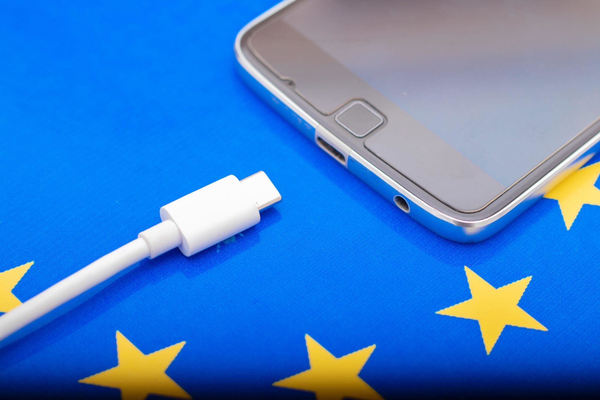 Close up of a mobile phone Charger with a USB Type - C cord on an EU flag.