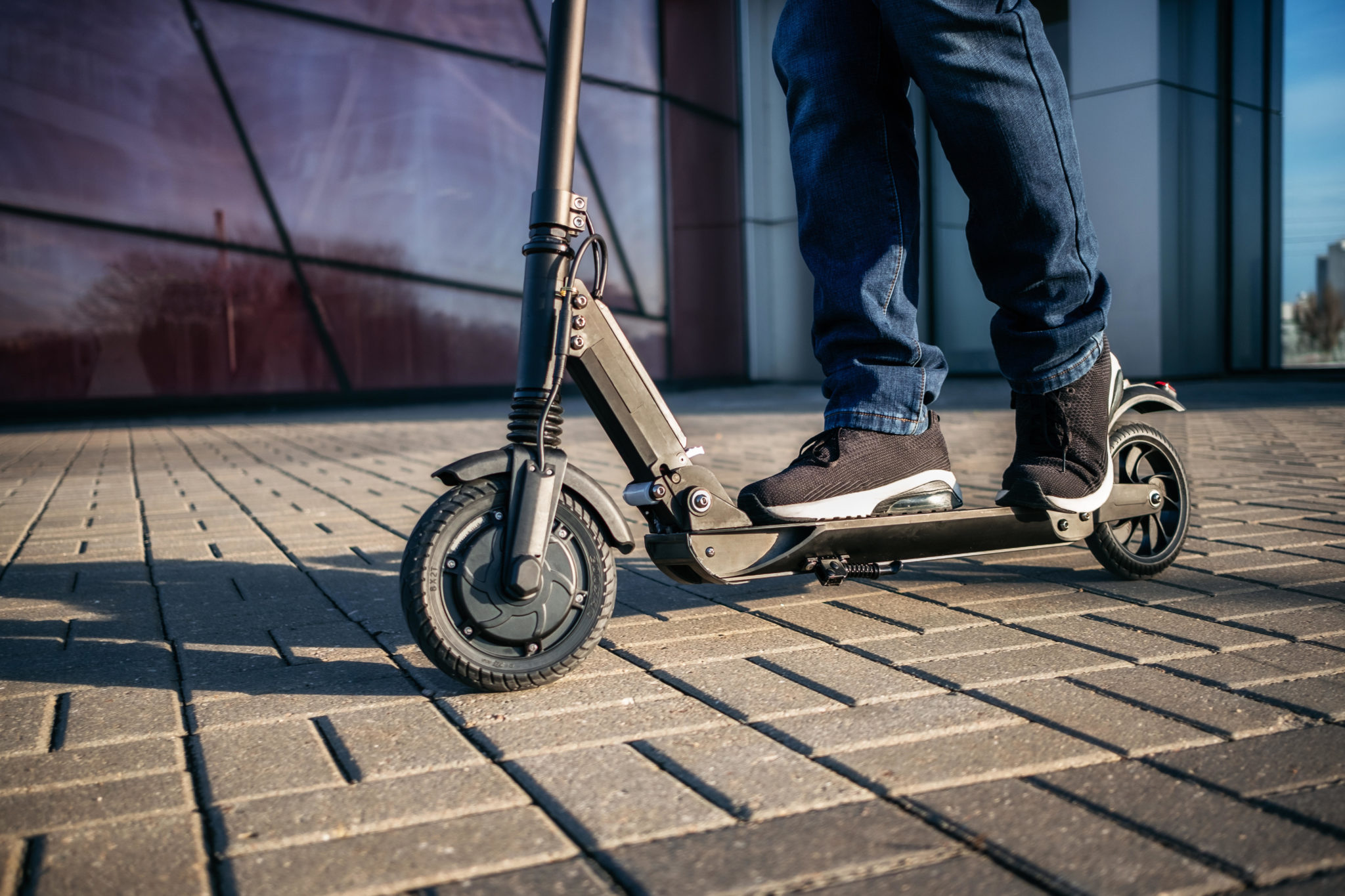Main image shows a close- up view of a person on an electric scooter.