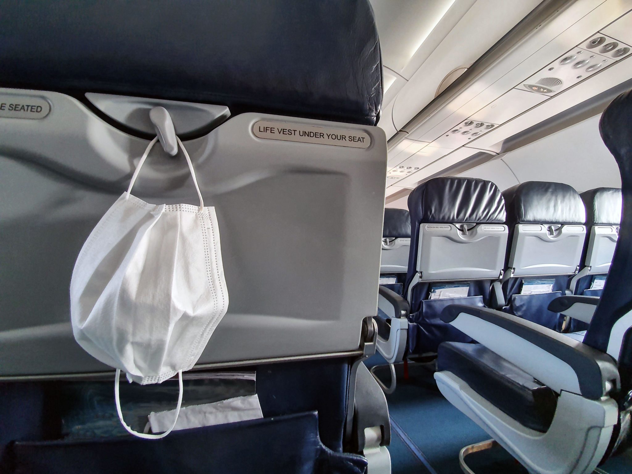 A medical white mask hangs in an airplane cabin in October 2020. 