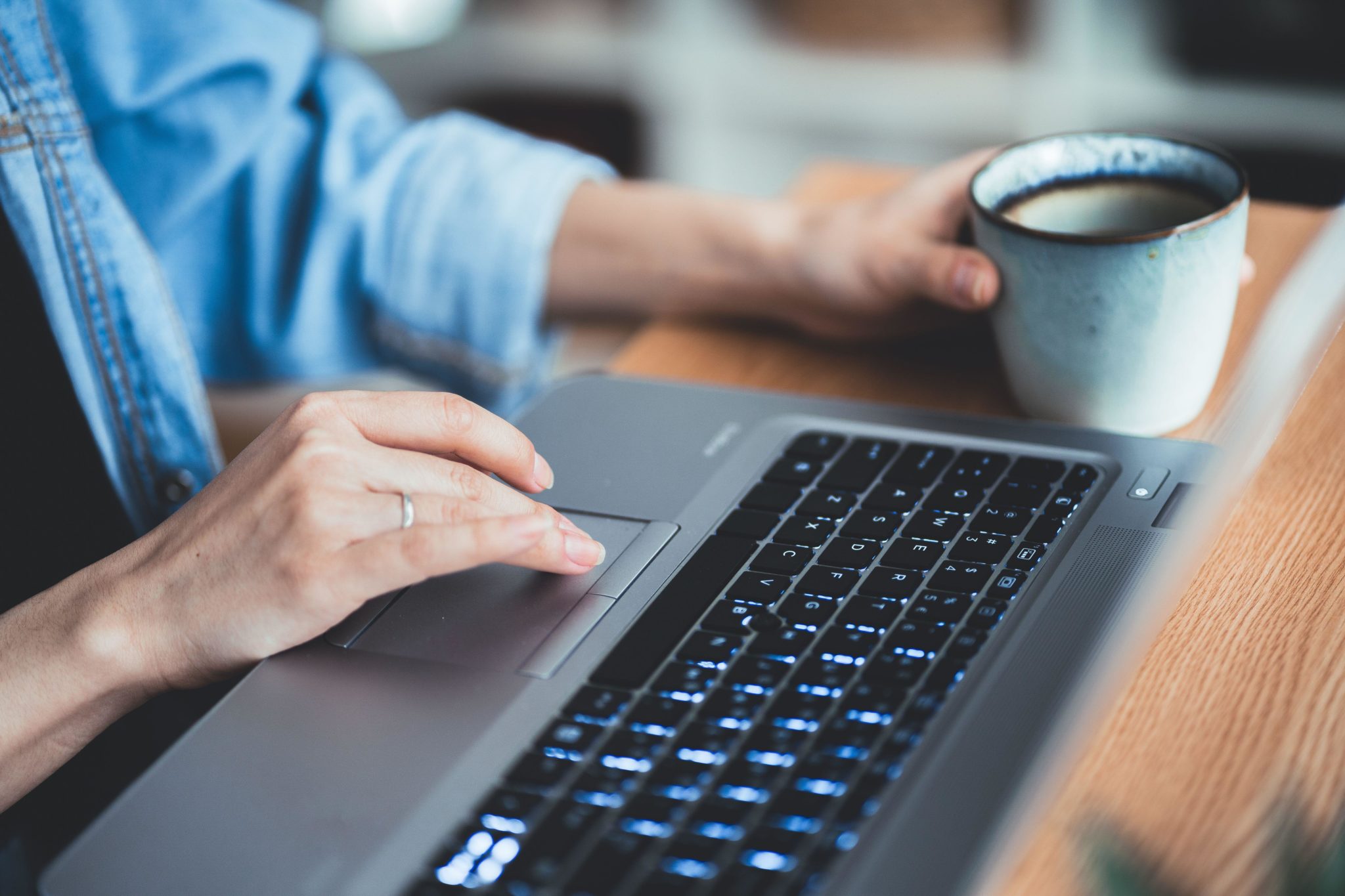 A women typing and scrolling on a laptop keyboard. 