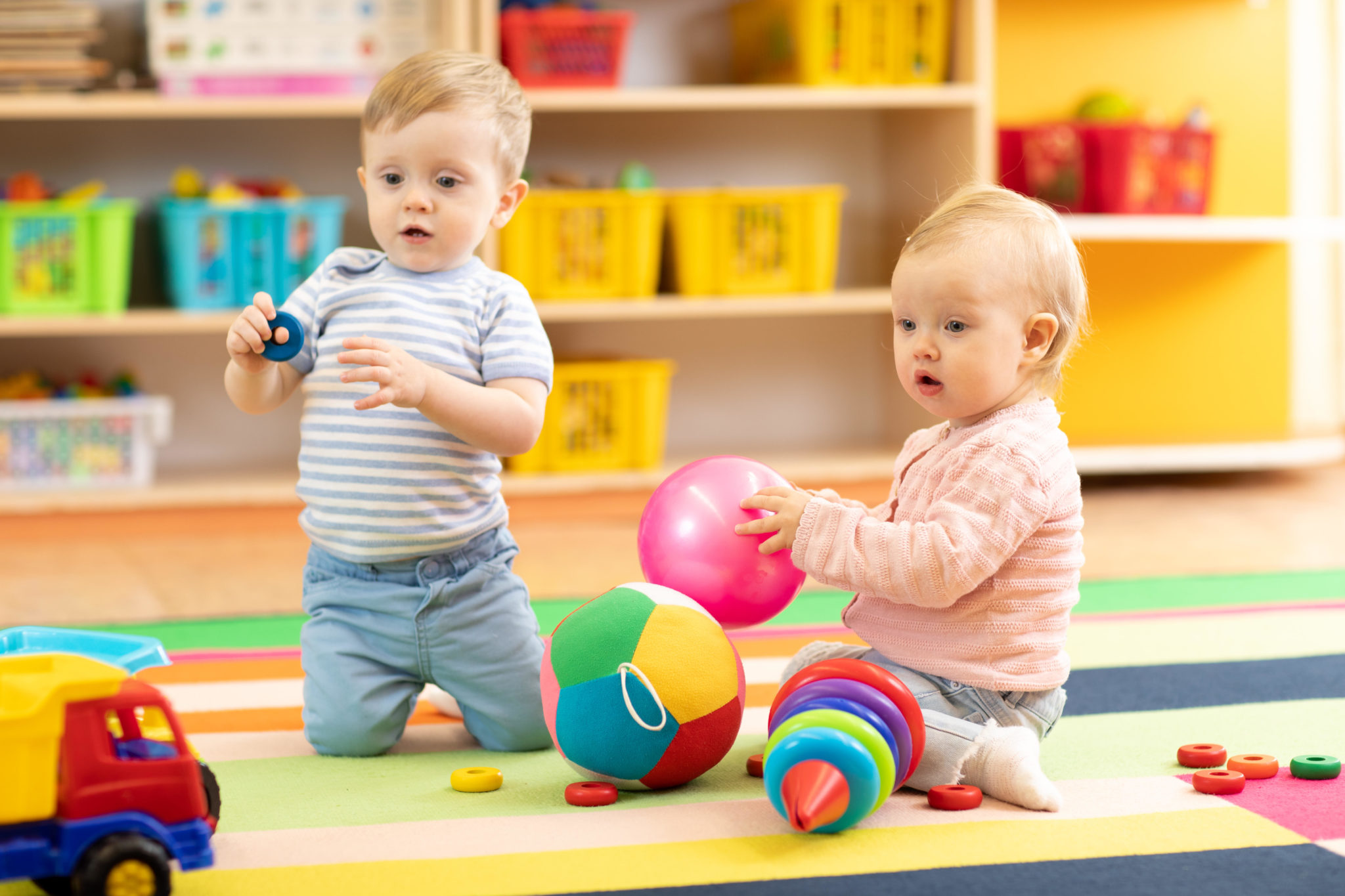 Babies playing on the floor with toys in a creche.