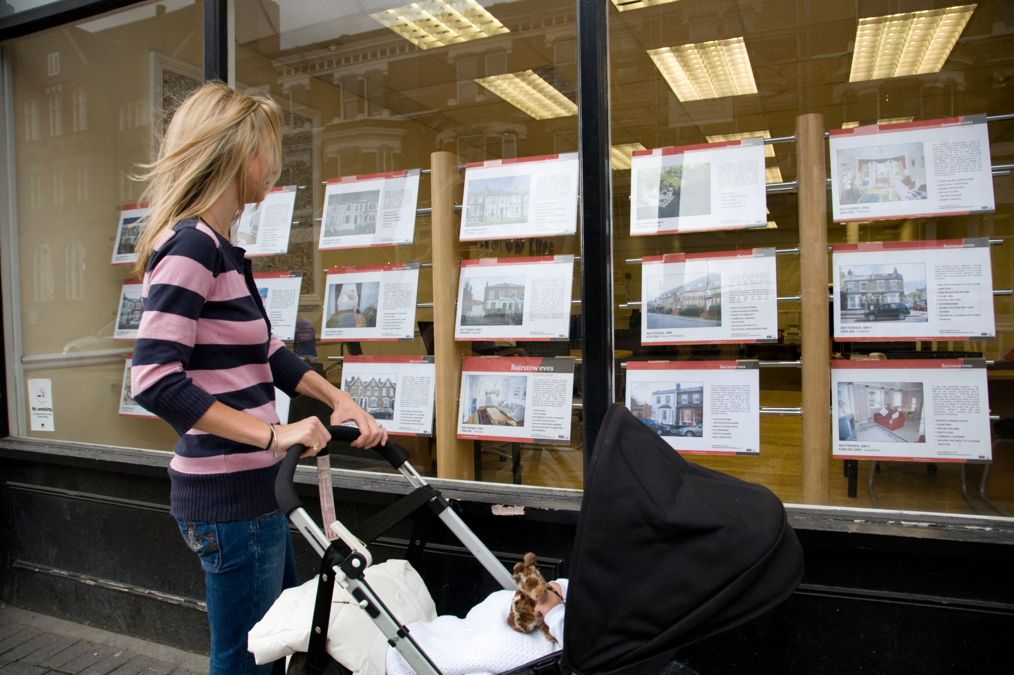 A woman looks at properties advertised for sale in an estate agents window in June 2008.