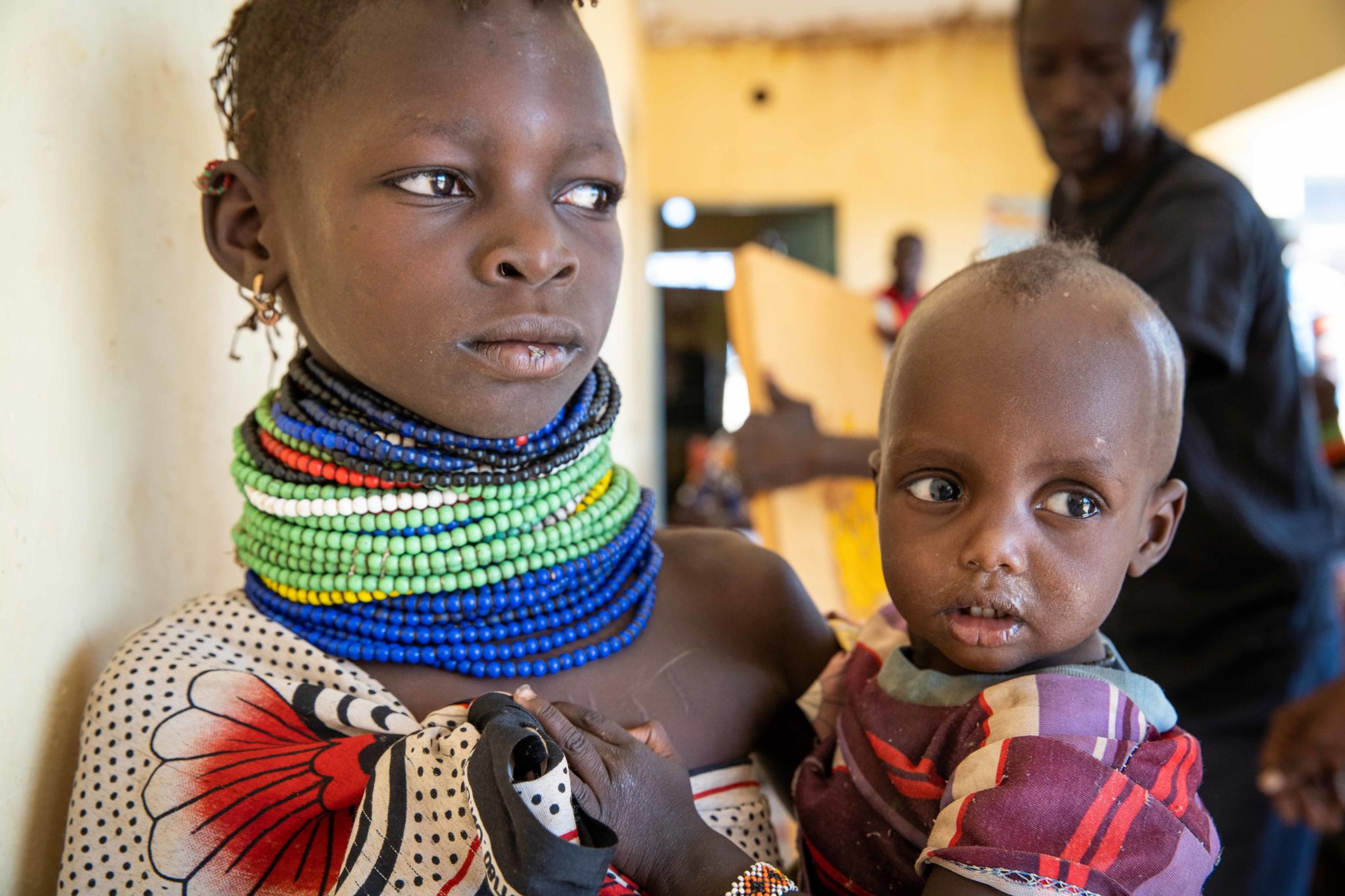 Ngirethi Ekakutan (L) holds her younger sister, Mary Ekakutan (R), as they wait to be seen at a malnutrition clinic in Lekwasimyen in Northern Kenya's Turkana province on 28th June 2022