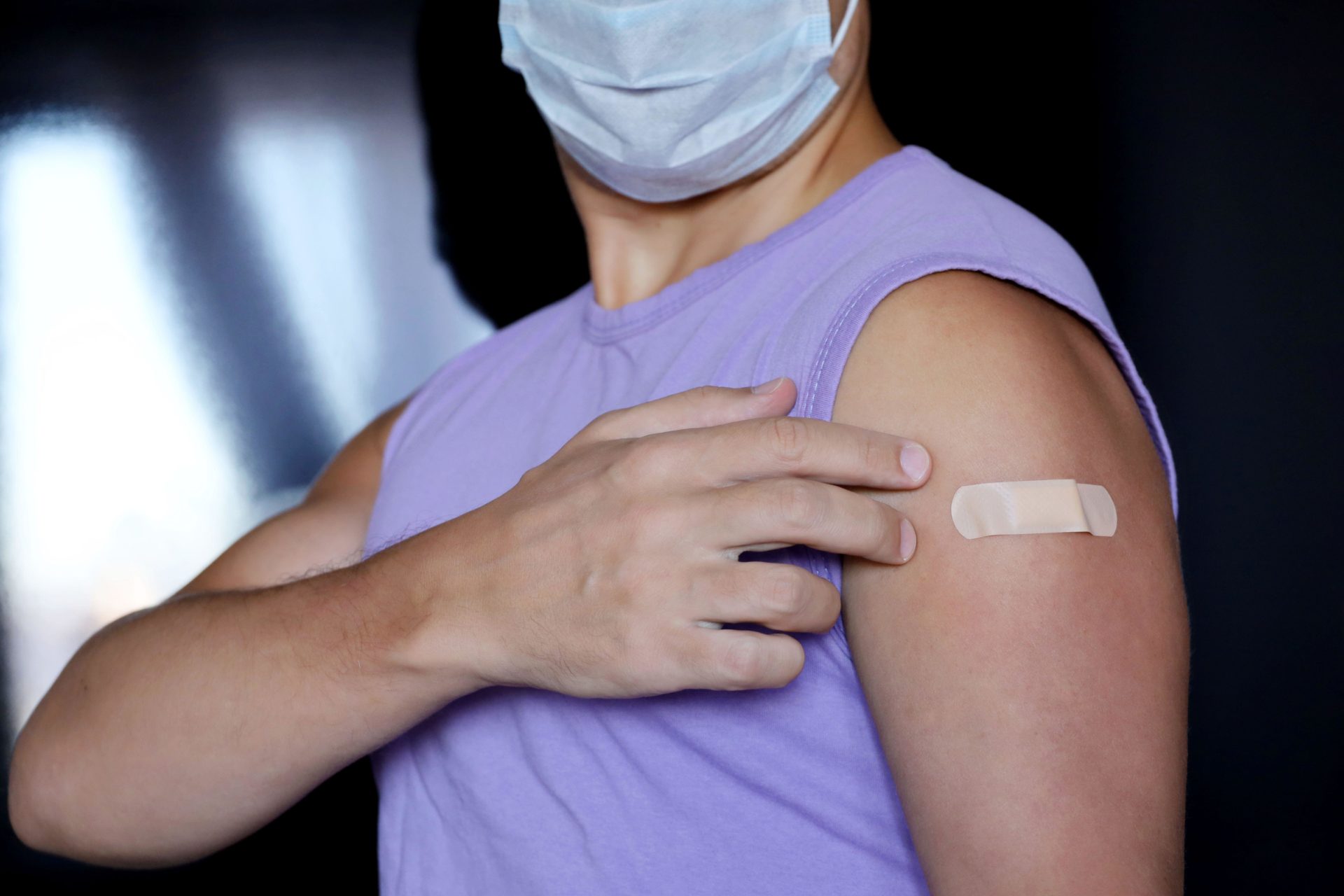 A man showing his arm with a bandage after receiving a vaccine.