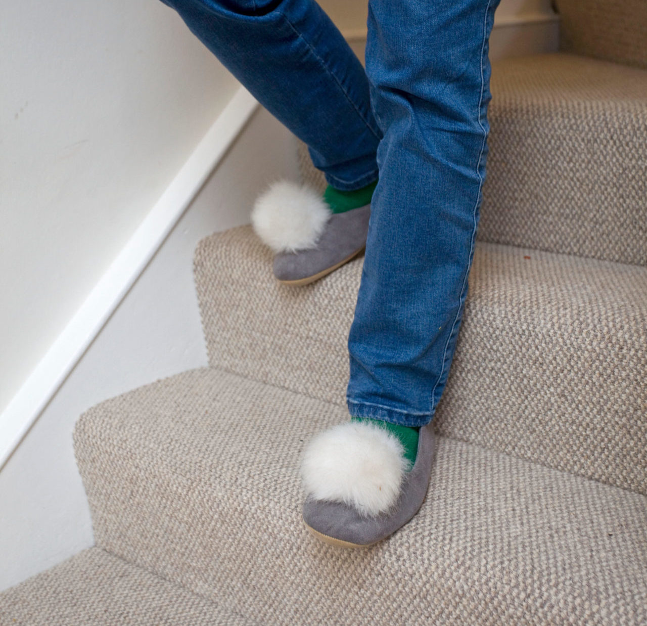 A woman walking down the stairs wearing slippers.