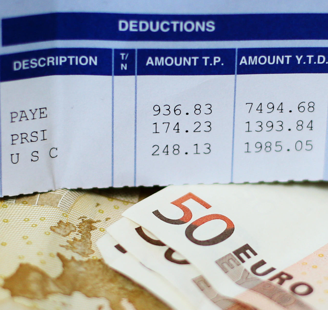 A payslip displaying tax deductions alongside €50 notes in 2014.