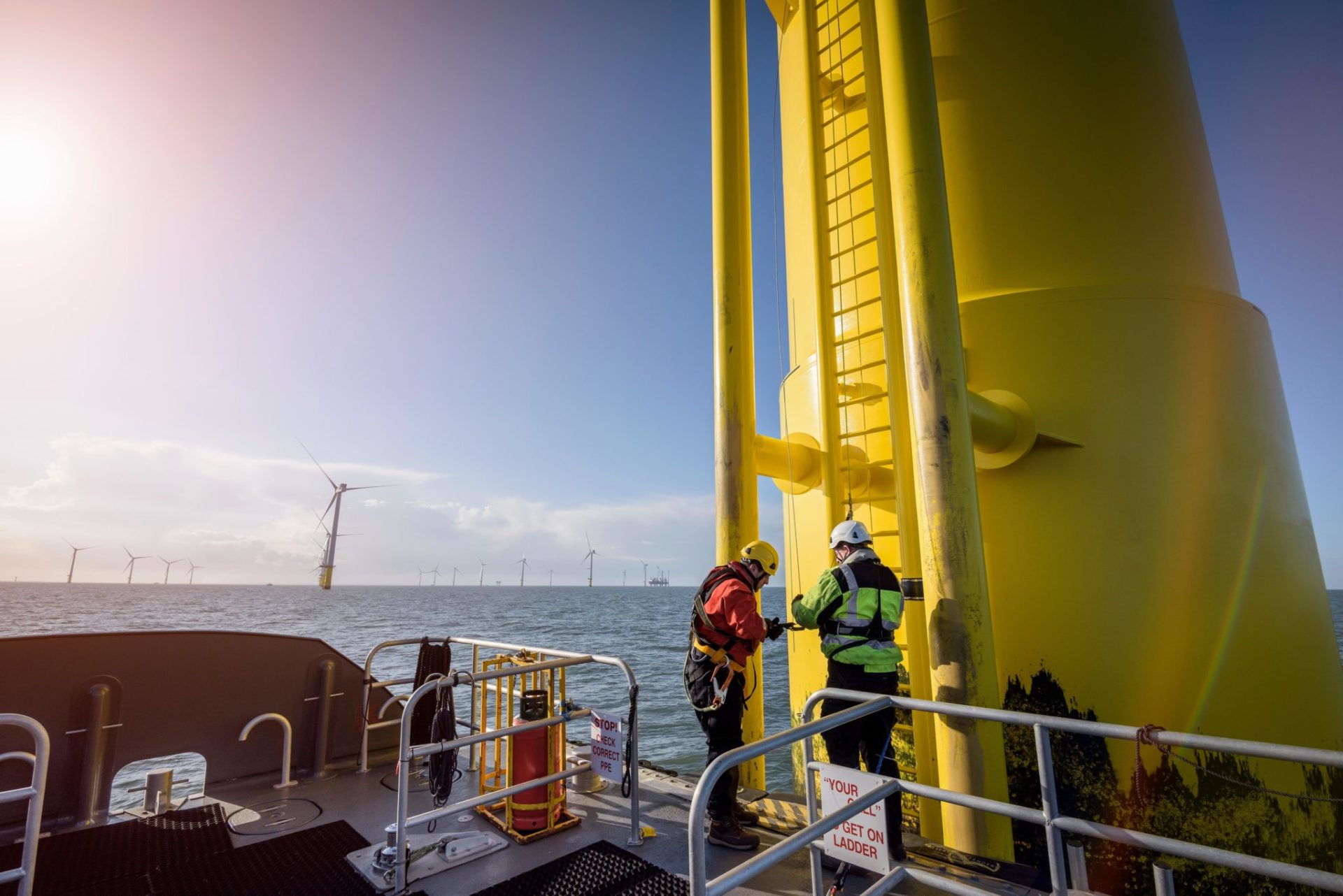 Engineers climbing wind turbine at offshore wind farm