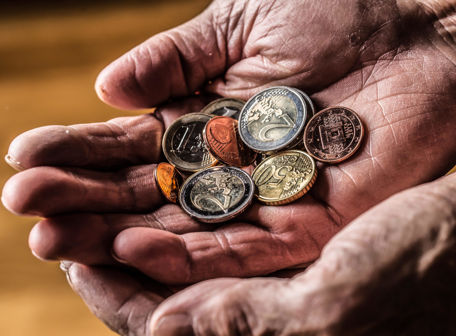 A pensioner holding euro coins in his hands.