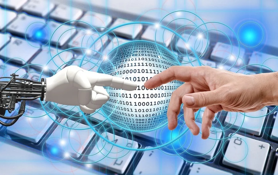 robots. Image shows a robotic hand and a human hand reaching out to each other in front of a computer keyboard.