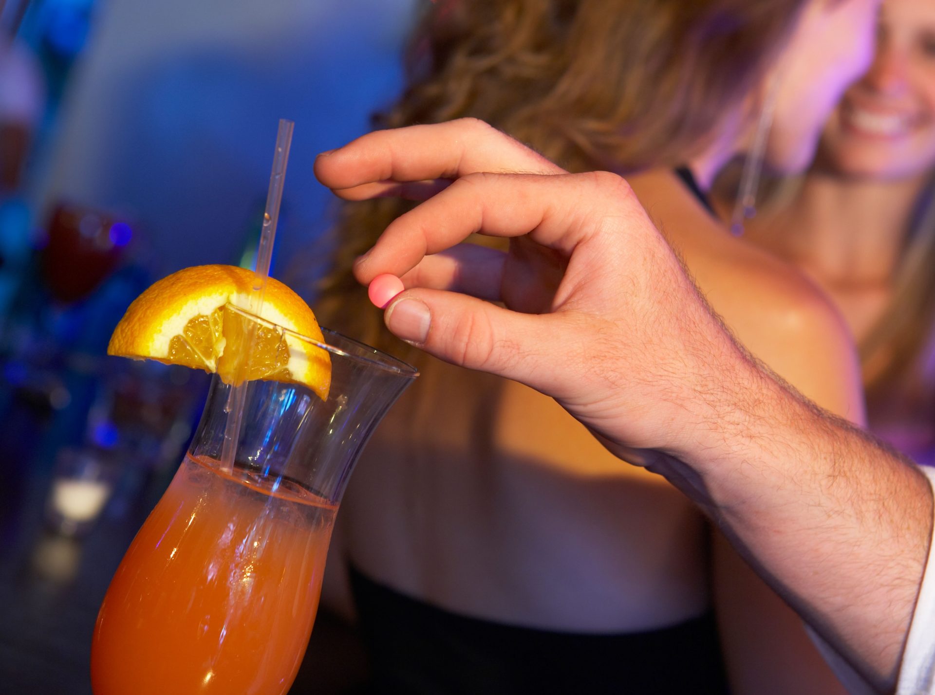 A person drugging a drink in a bar.