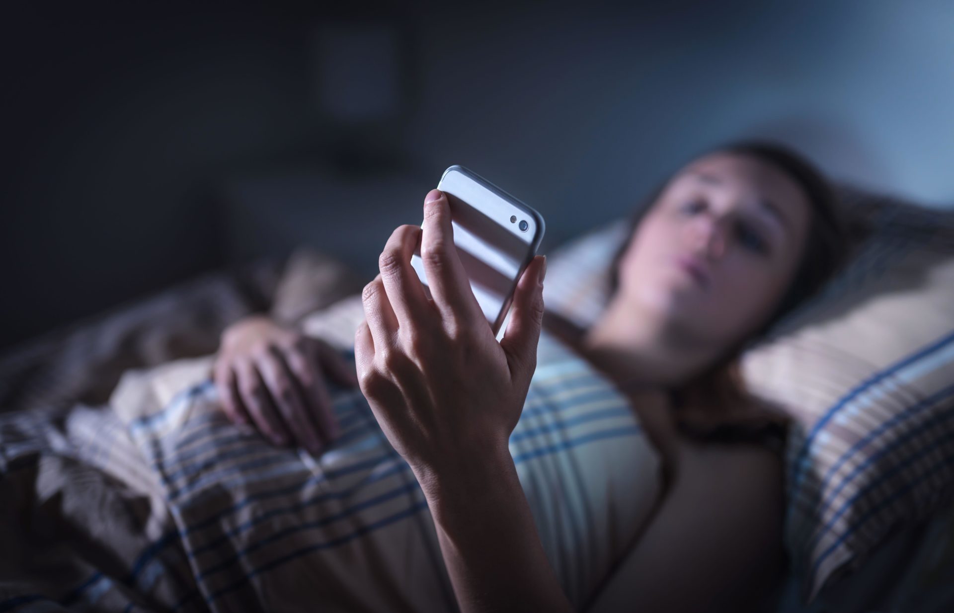 Woman looking at smartphone at night in bed. Image: Tero Vesalainen / Alamy