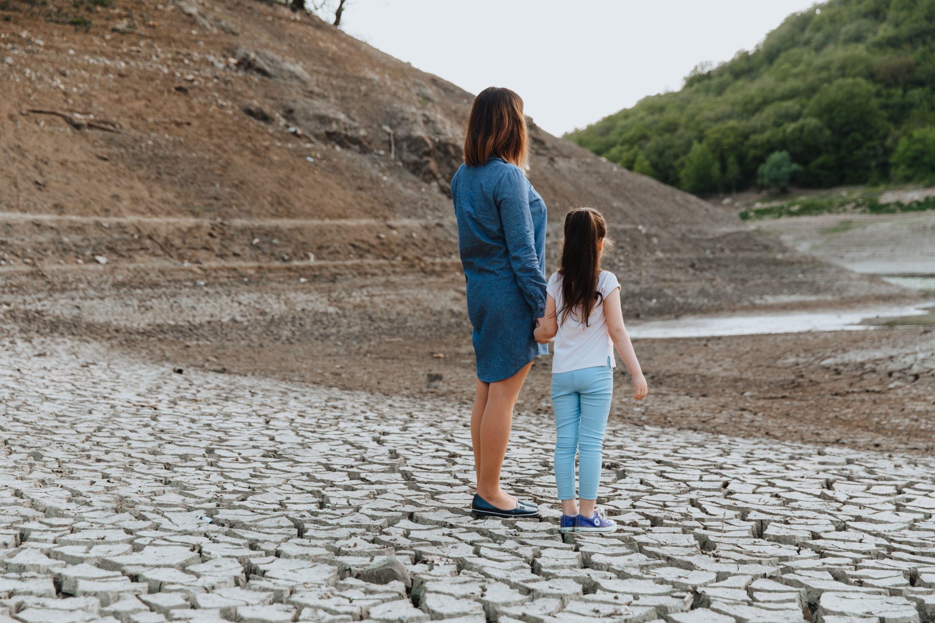 A mother and child stand in front of a disappearing lake.