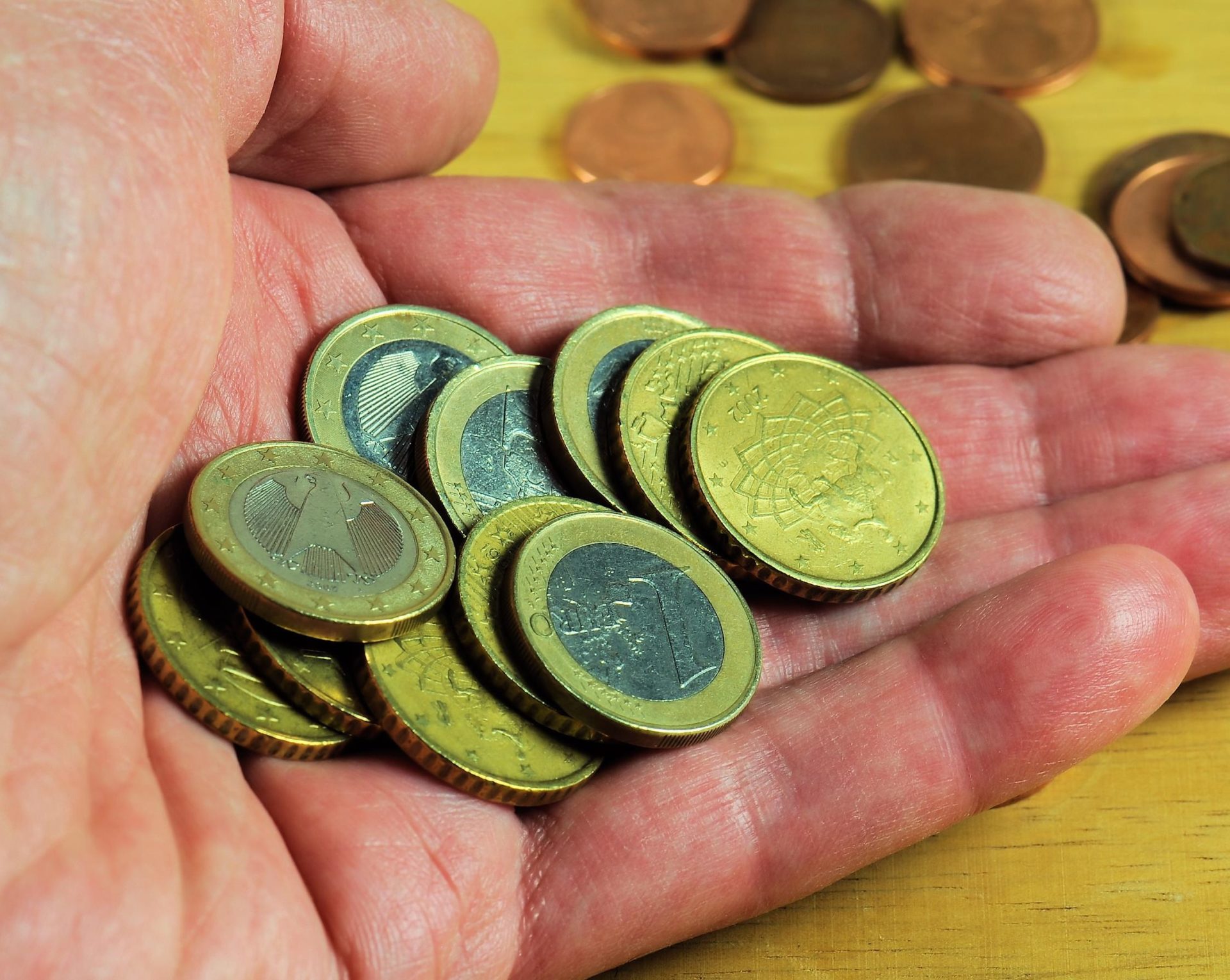 A man's hand holds Euro coins.