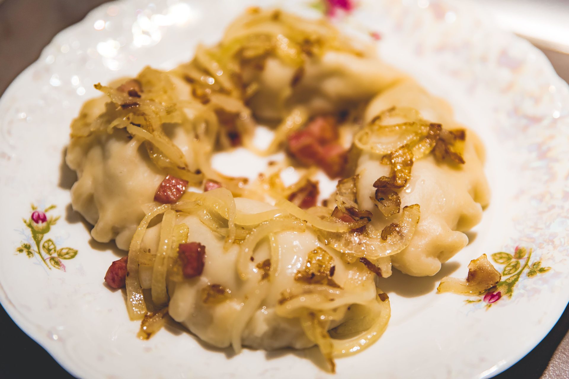 Traditional Polish homemade dumplings - pierogis - on a plate served with fried onion and baco