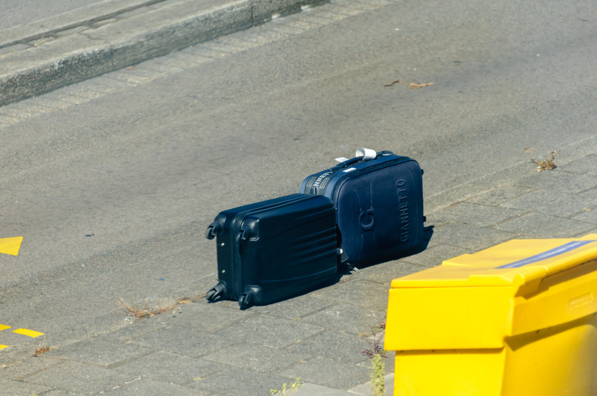 Passenger luggage suitcases lie on an airport road after falling off a baggage truck
