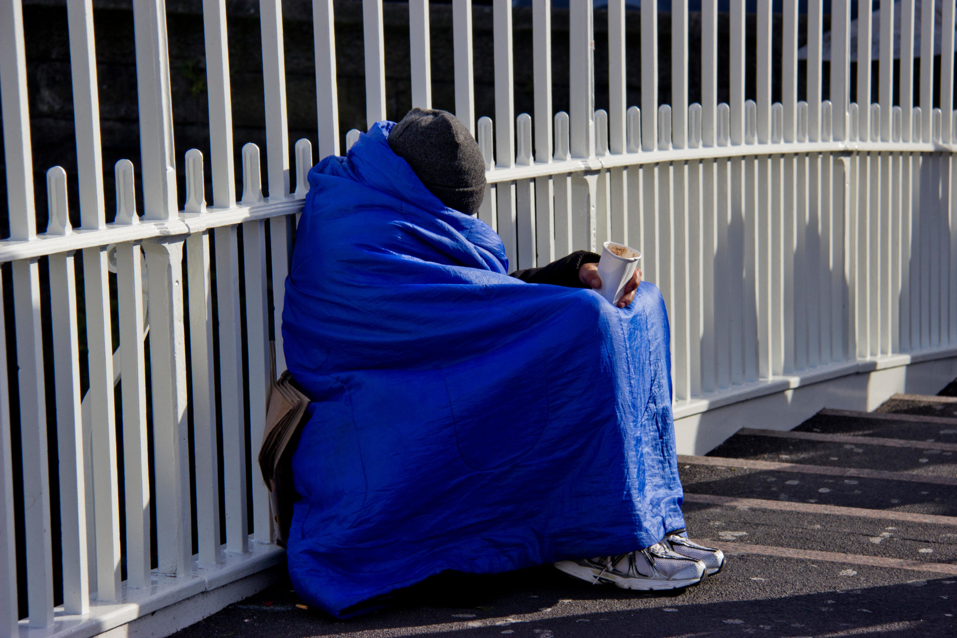Homeless person shelters from the cold Ha’penny Bridge in Dublin. Image: Michael Rooney / Alamy