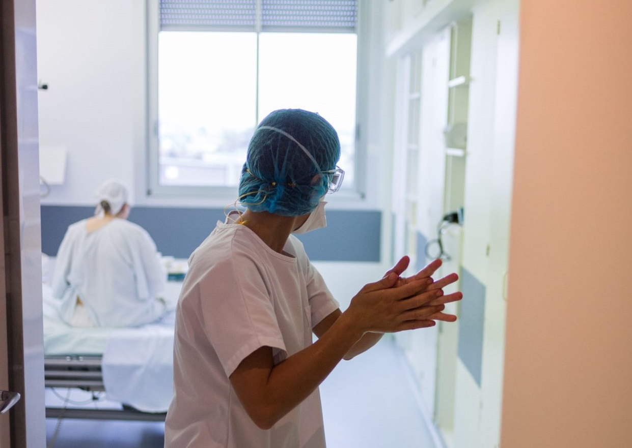 A nurse washing her hands leaving a room of a COVID hospital unit.