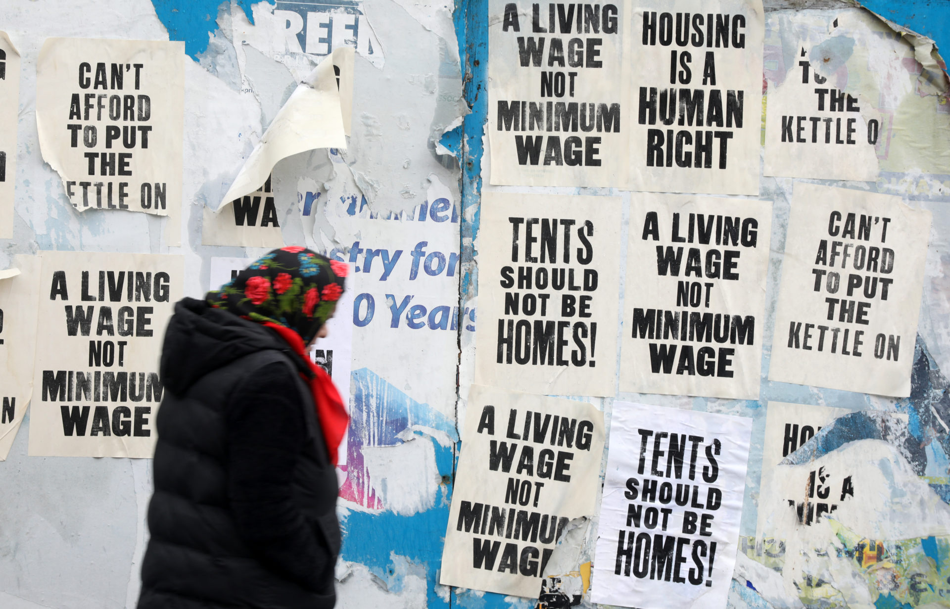 A woman walks past a billboard with posters protesting homelessness on Bow Lane, West Dublin