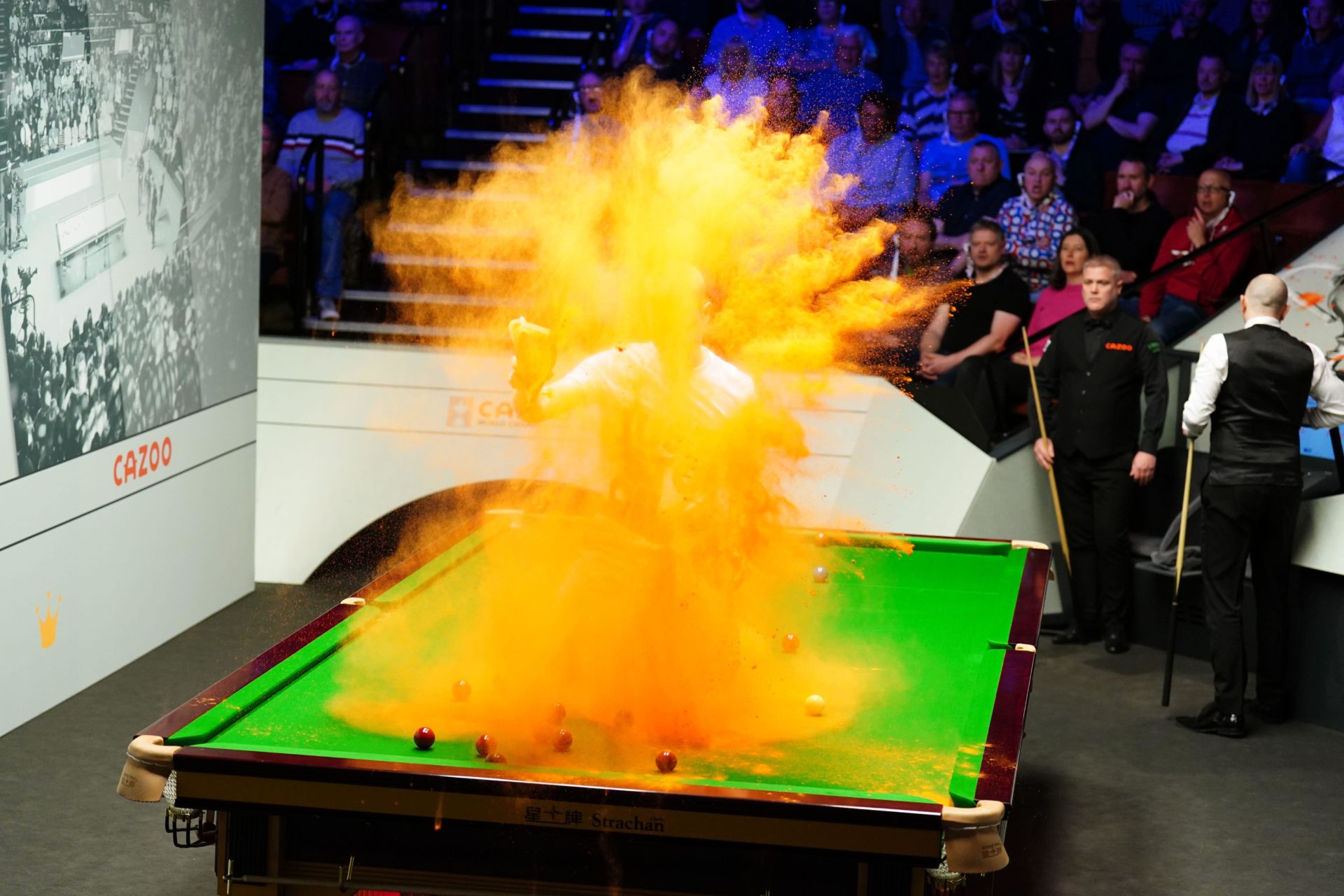 A Just Stop Oil protester jumps on the table and throws orange powder during the World Snooker Championship in Sheffield
