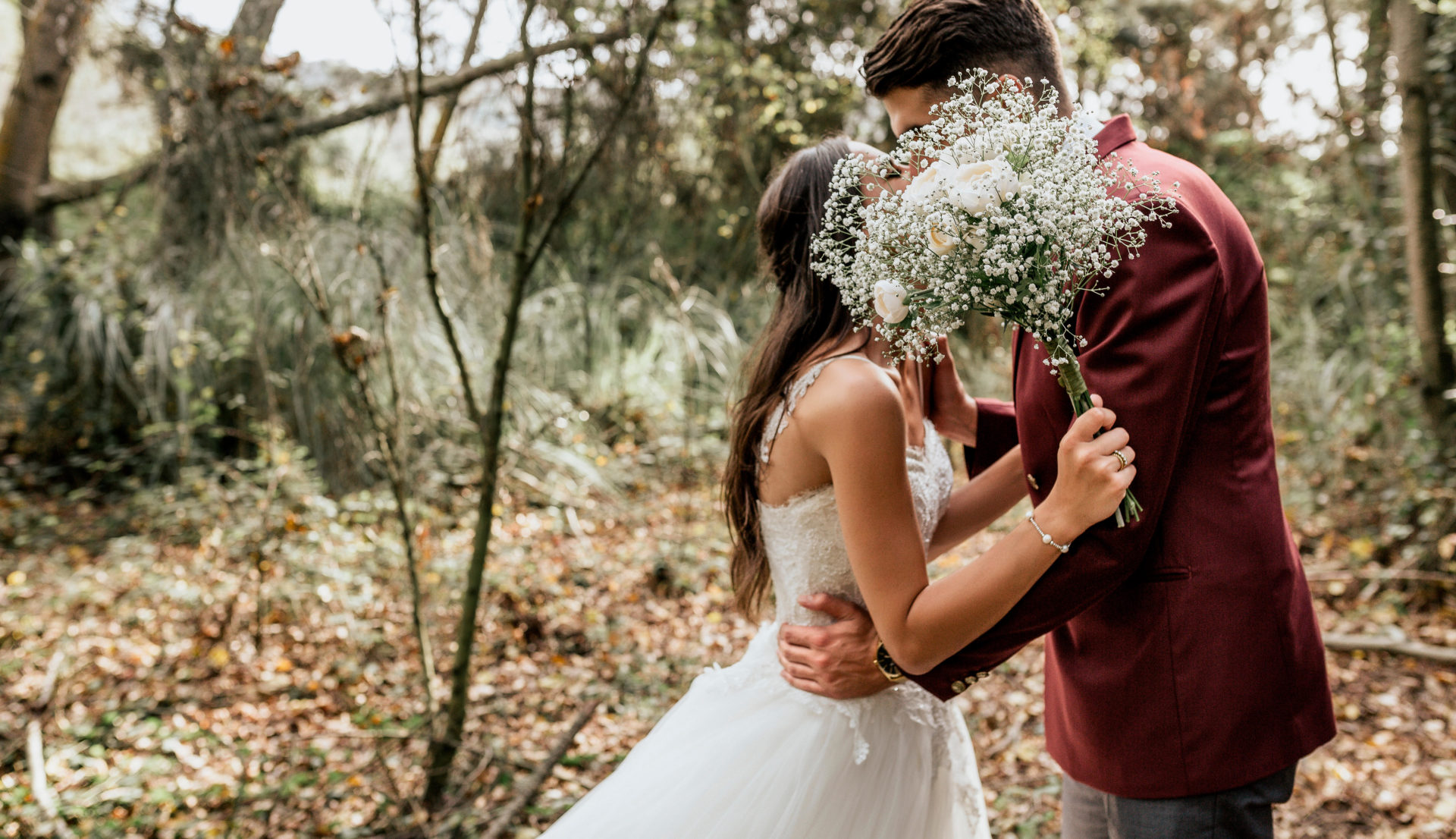 A bride and groom kissing in a forest.