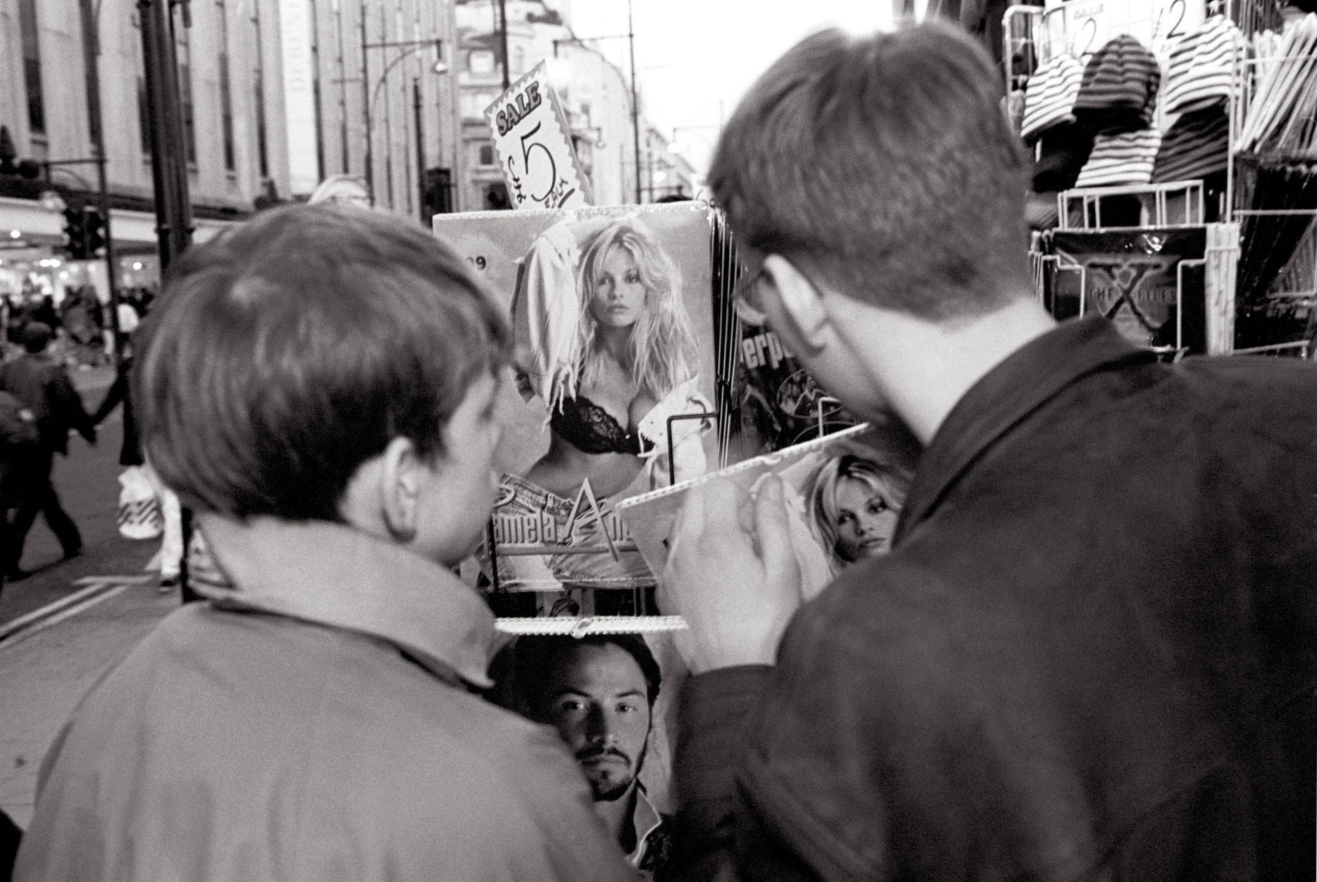 Boys looking at Pamela Anderson calendar in Oxford street London 