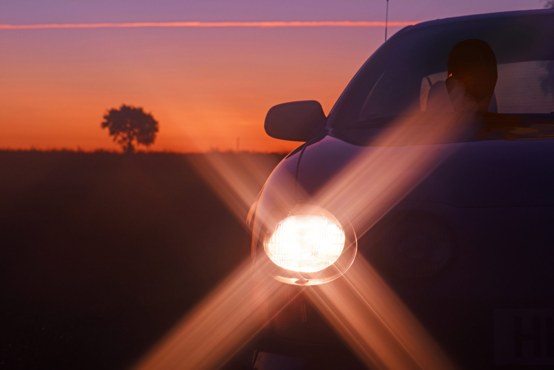 Car with headlights on country road at sunset york yorkshire united kingdom (riddypix / Alamy Stock Photo)